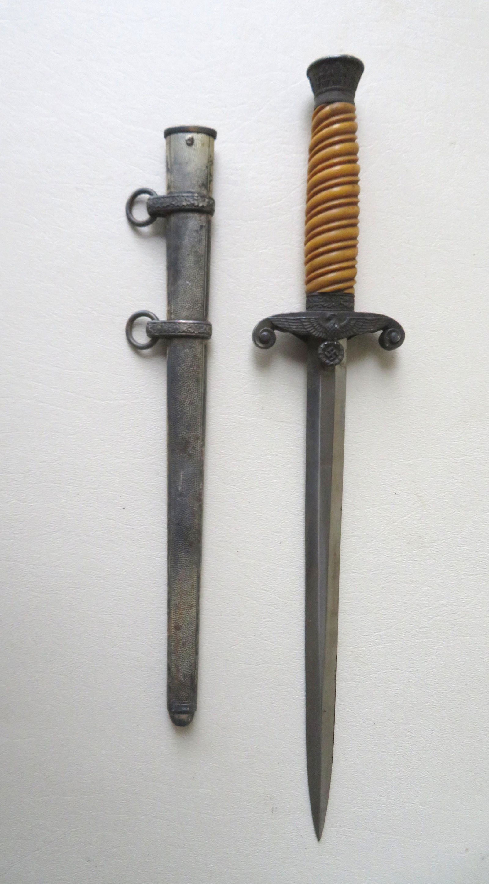 A WWII German Army dagger with scabbard, signed Eikhorn: A WWII German Army dagger with scabbard, signed Eikhorn below squirrel mark. The dagger with a metal crown, yellow celluloid swirled grip, scrolled cross guard with eagle above insignia within wreath.