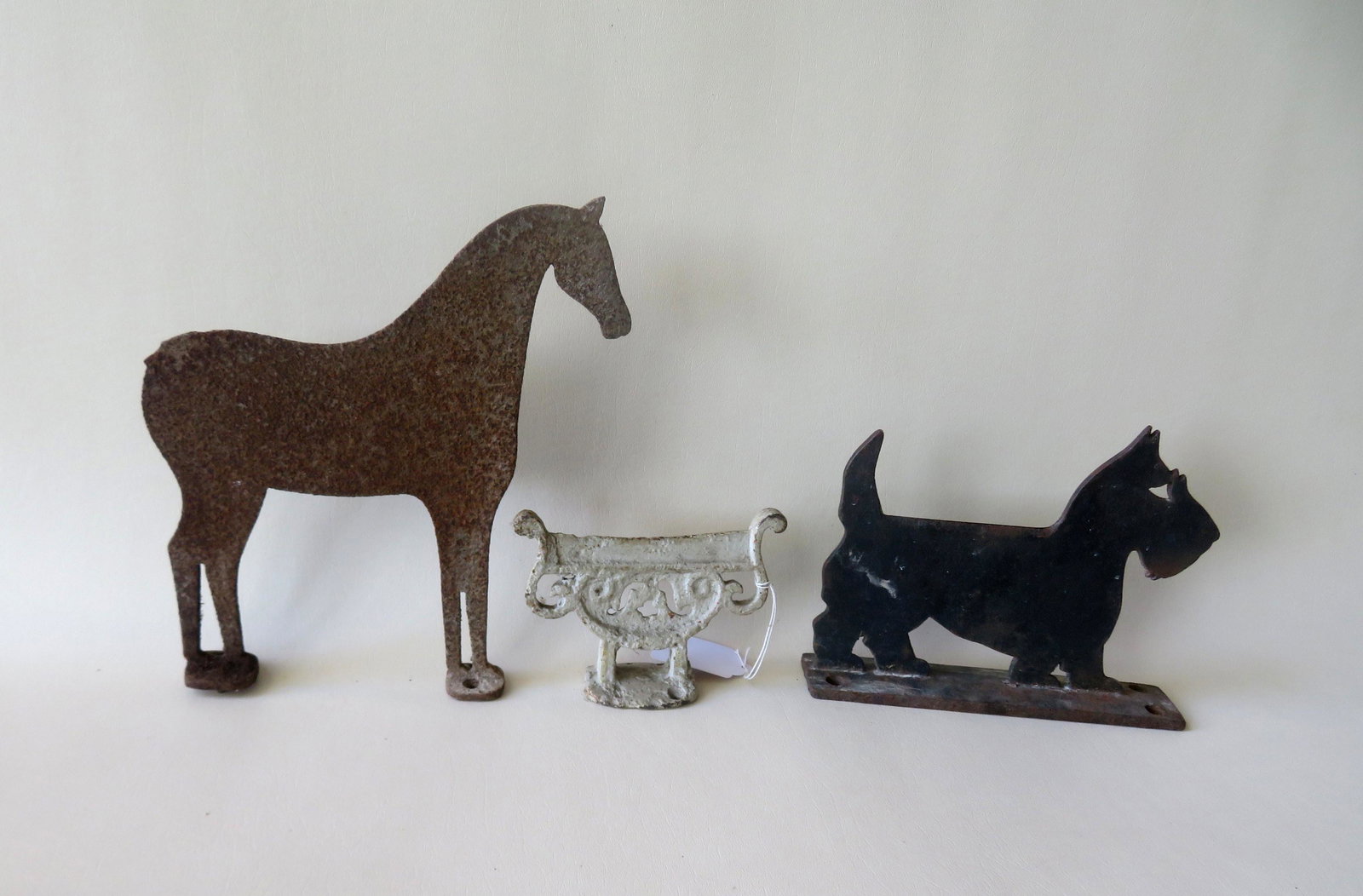 Three cast iron silhouette boot scrapers including: A: Three cast iron silhouette boot scrapers including: A Scotty Dog in original black paint - 10"L x 2 1/4"W x 7 3/4"H - very good original condition; a horse missing tail - surface rust - 11 1/2"L x 12 