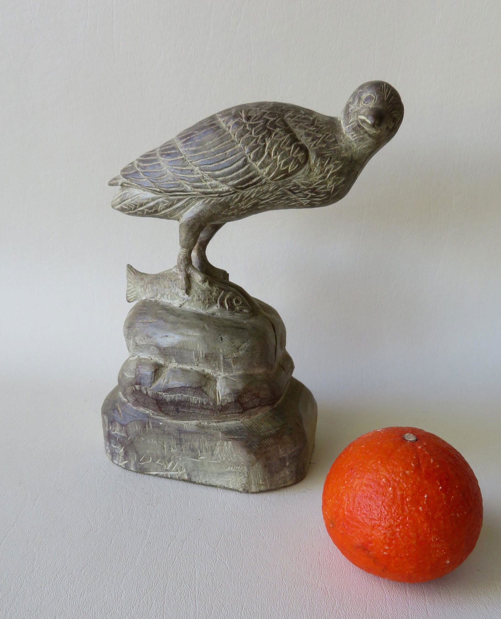 A carved bird with talons holding fish on rock pile,: A carved bird with talons holding fish on rock pile, signed L. Davis. Probably mid 20th century. Very good condition. 9"H x 5 1/4"W x 4"D.