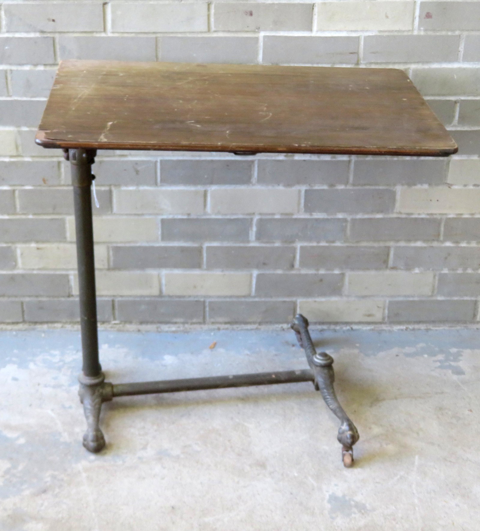 A writing table with adjustable top and iron base with: A writing table with adjustable top and iron base with chicken legs and chicken feet, late 19th century, signed Knauth Bros. New York. The top with some veneer losses, but overall good condition. 27" 