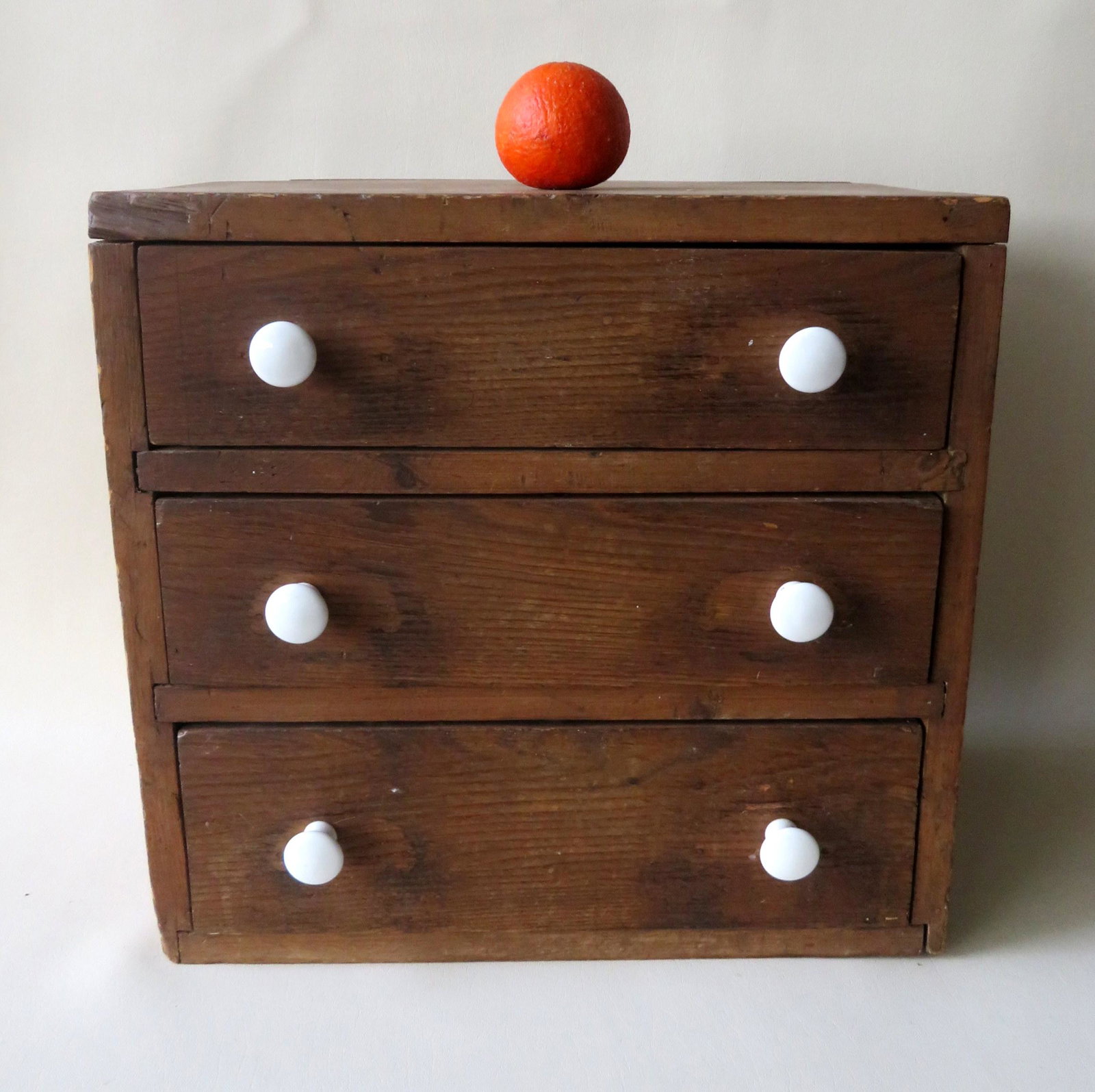 A small 3 drawer table top storage unit in brown stain,: A small 3 drawer table top storage unit in brown stain, 19th century with newer porcelain pulls. Very good condition. 18"W x 12"D x 17 1/4"H.
