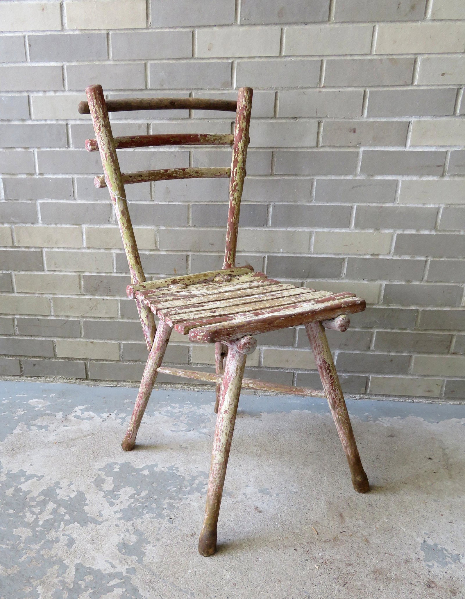 A primitive and rustic wooden chair with layers of old: A primitive and rustic wooden chair with layers of old paint and cross stretchers - worn hoof feet and 1 cross stretcher is loose from joint, otherwise good condition. Early 19th century. 17"W x 16"D 