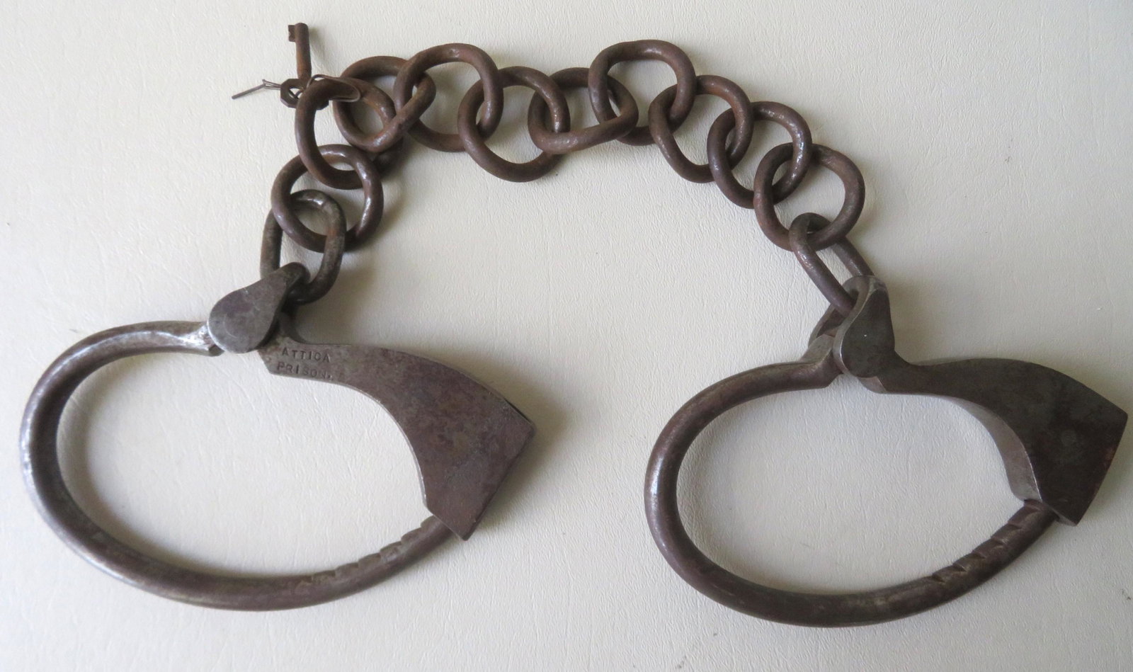 A pair "Attica Prison" leg irons with key.: A pair of signed "Attica Prison" leg irons with key - the key turns but does not release locks, otherwise they are in good condition.