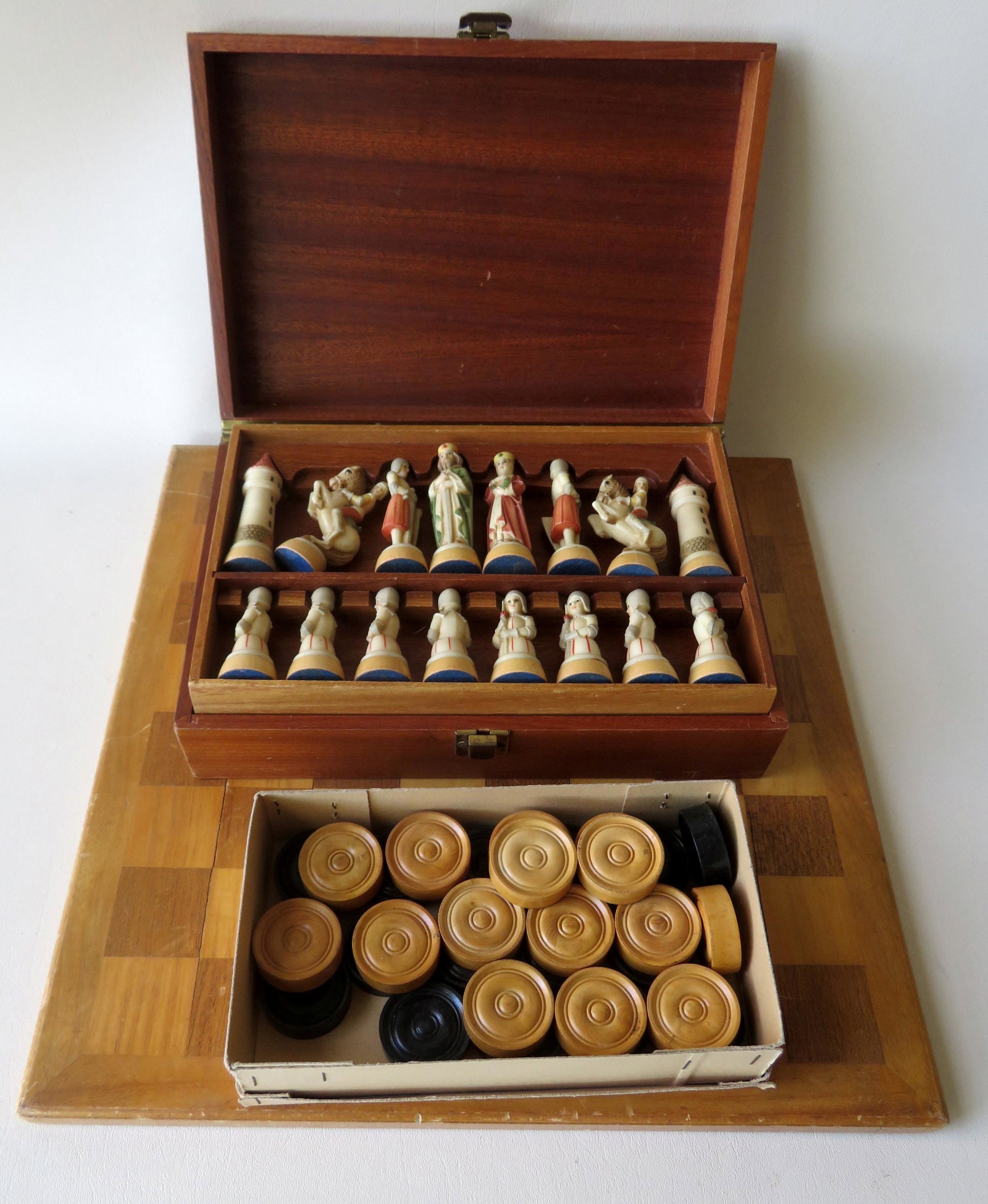 A modern inlaid wooden game board with large wooden: A modern inlaid wooden game board with large wooden checkers in original cardboard box and composition chess set in original wood box with medieval figures. All in very good condition. The board measu