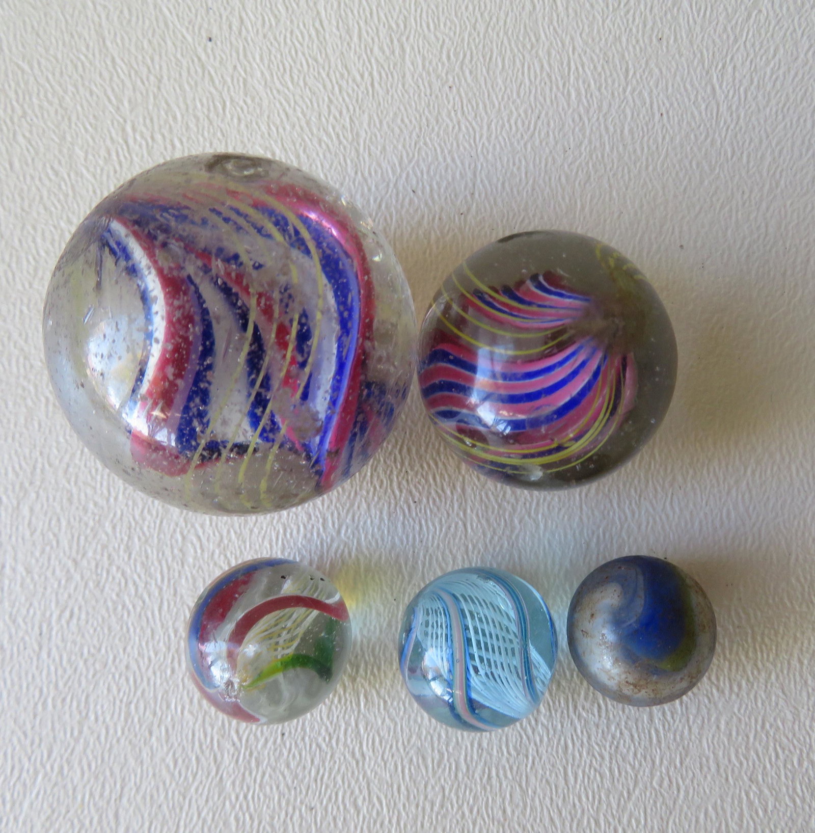 Grouping of 5 vintage glass marbles, 4 hand blown, late: Grouping of 5 vintage glass marbles, 4 hand blown, late 19th to early 20th century, ranging in size from 5/8"D to 1 1/2"D. Most with imperfections including surface chips and use wear. See photos for 