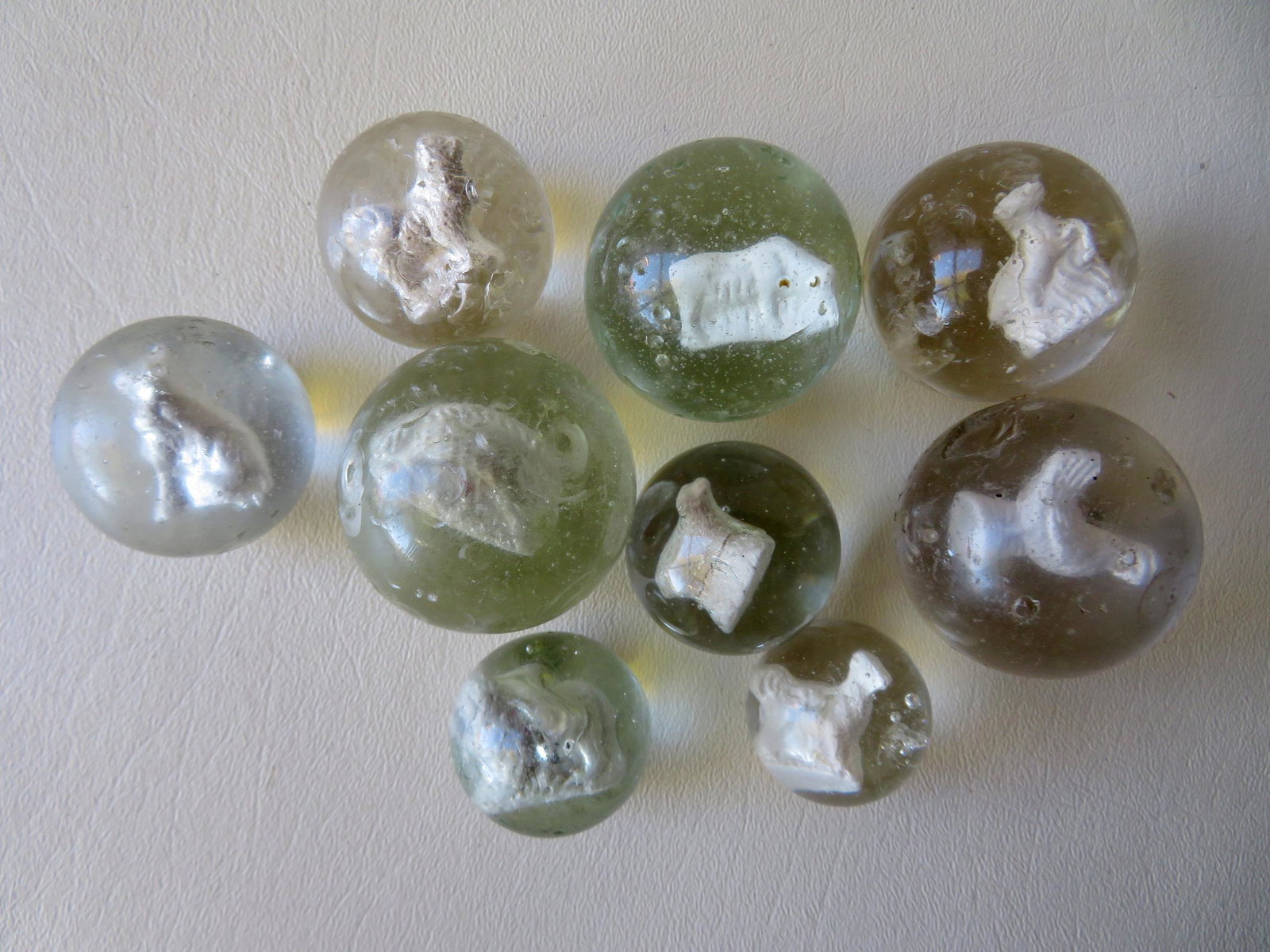 Grouping of 9 sulfide marbles including: Cow - 1 5/8"D;: Grouping of 9 sulfide marbles including: Cow - 1 5/8"D; dog - 1 3/8"D; rooster - 1 5/8"D; leaping horse - 1 1/2"D; an unknown animal, probably a hedgehog - 1 5/8"D; seated dog - 1 3/8"D; lamb - 1 1/4"