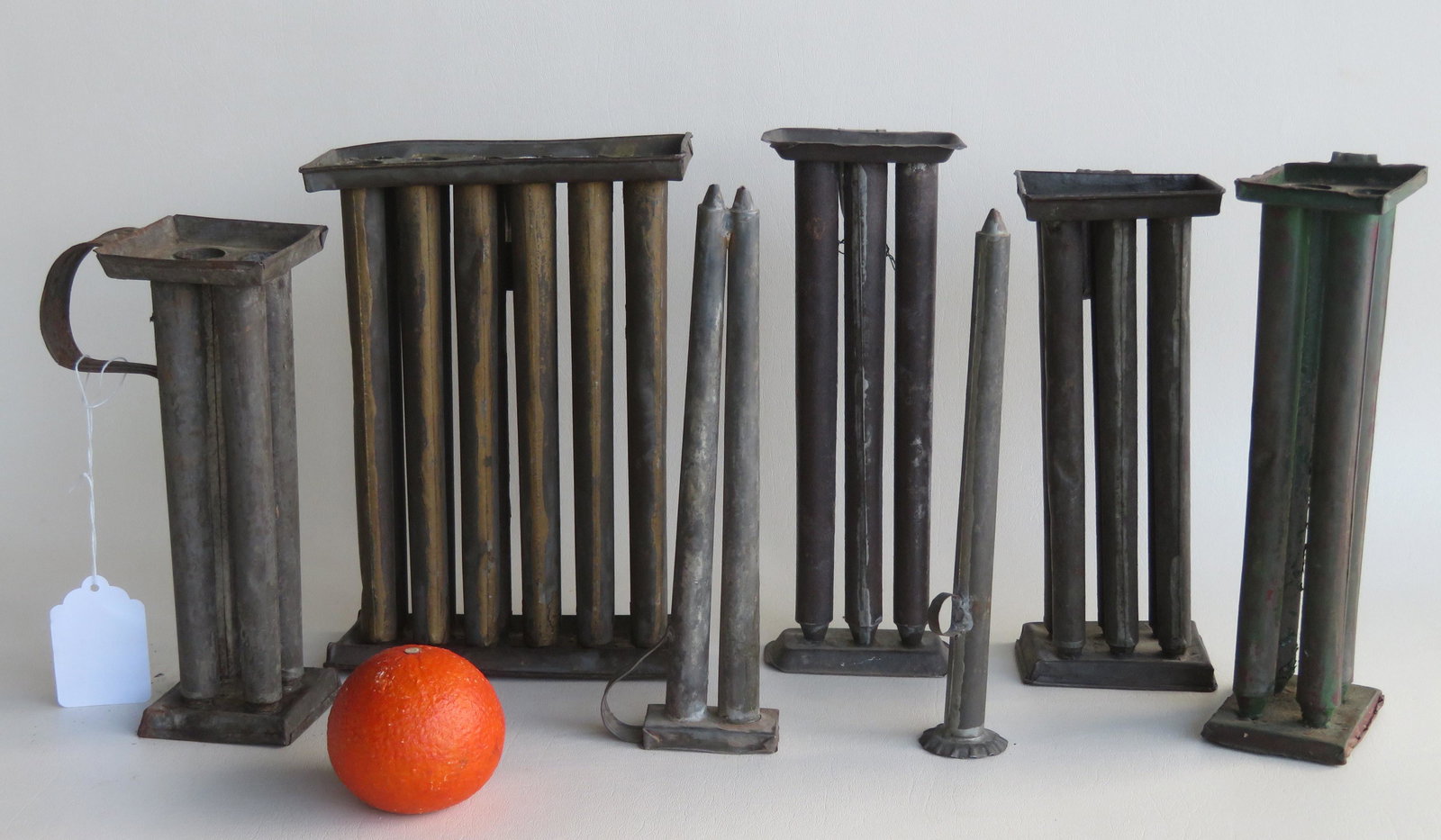 A grouping of 7 tin candle molds including: 1 single: A grouping of 7 tin candle molds including: 1 single 10"H, 1 double 10"H, 1 three mold 10 3/4"H, 2 four molds (1 of these in green paint), 1 six mold 10"H, and 1 twelve mold 10 1/4"H. All used with mi