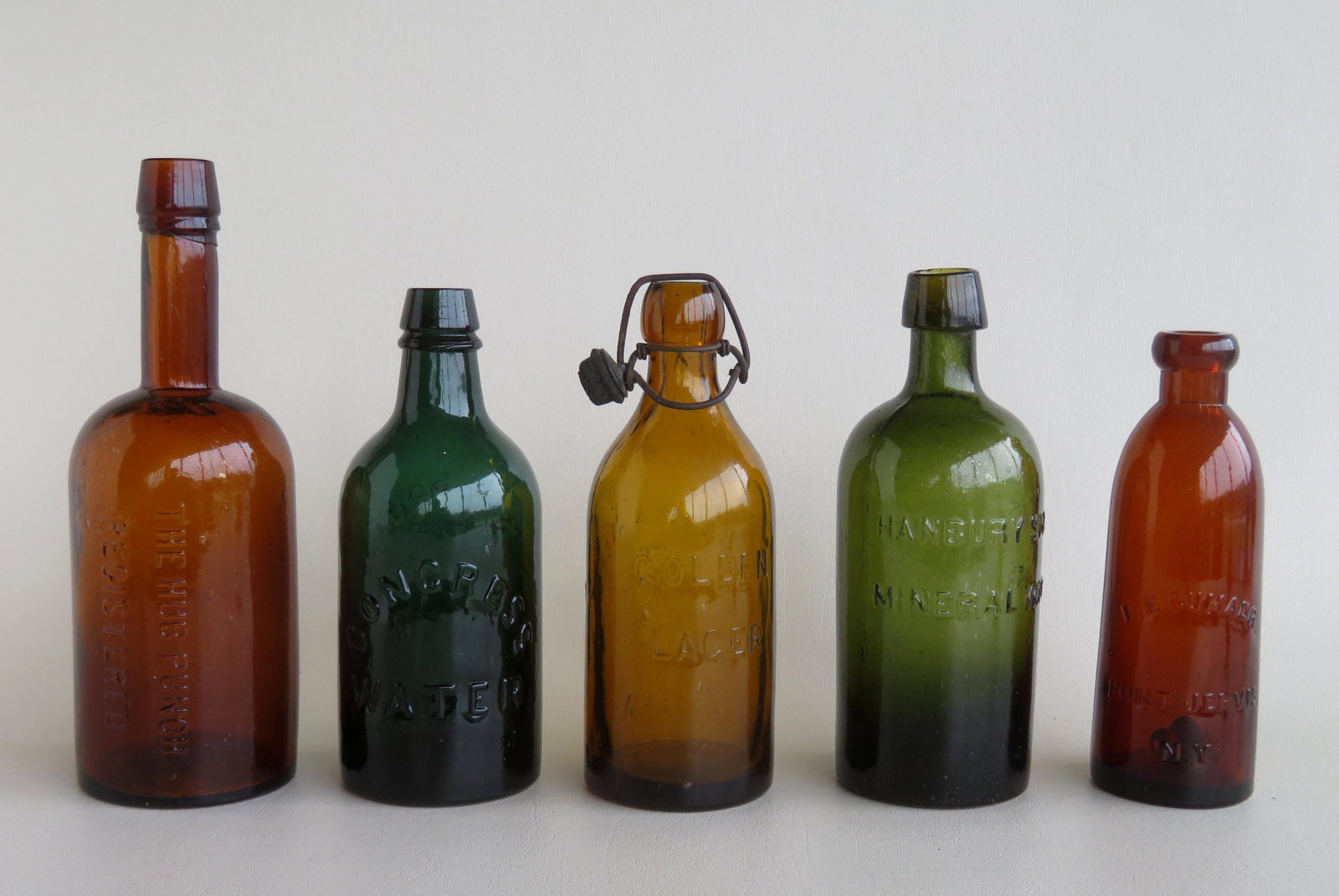 Grouping of 5 bottles including: An olive green: Grouping of 5 bottles including: An olive green "Hanbury Smith's Mineral Waters" bottle with sloping collared mouth - very good condition - 8"H; a dark green "Congress and Empire Spring Co. Saratoga N