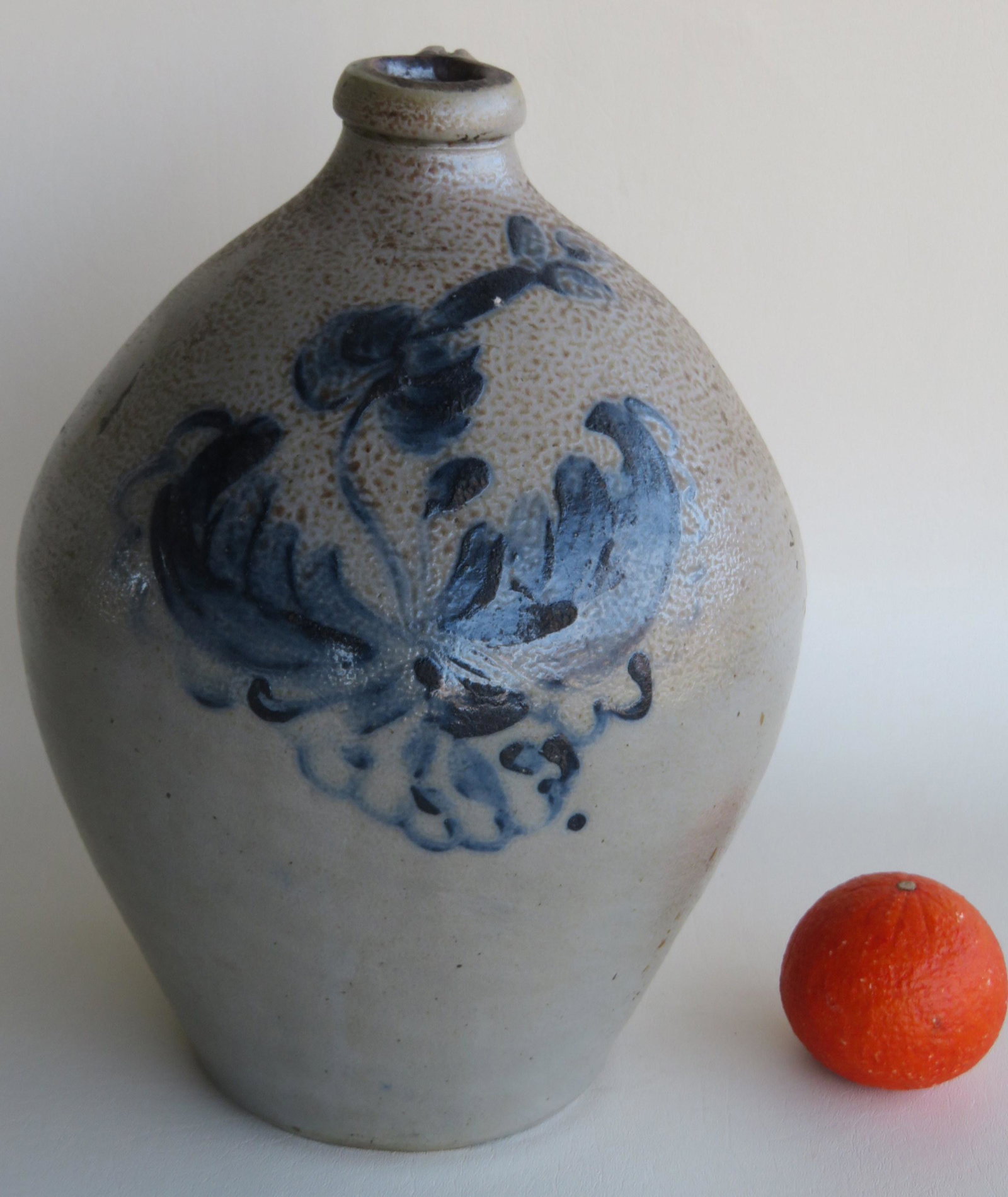 A beautiful stoneware ovoid crock with large cobalt: A beautiful stoneware ovoid crock with large cobalt blue flower having a tooled handle with blue brush markings - a small 1"L tight hairline extending from base which may have been done in the firing