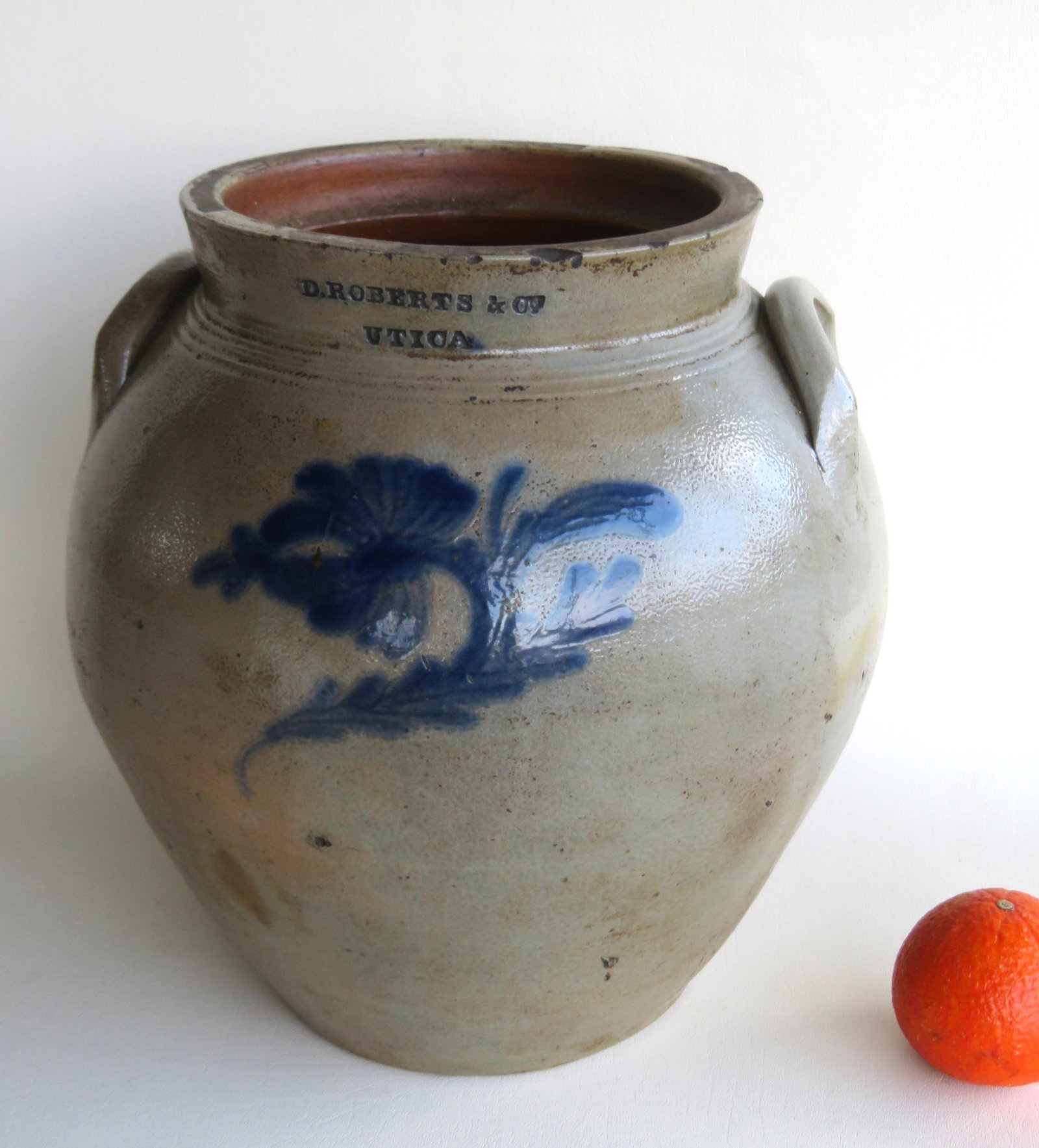 An early ovoid stoneware crock with cobalt blue flower: An early ovoid stoneware crock with cobalt blue flower having an impressed mark of D. Roberts & Co. Utica, circa 1830 - concentric lines around high collar. Several small rim chips, else very good con