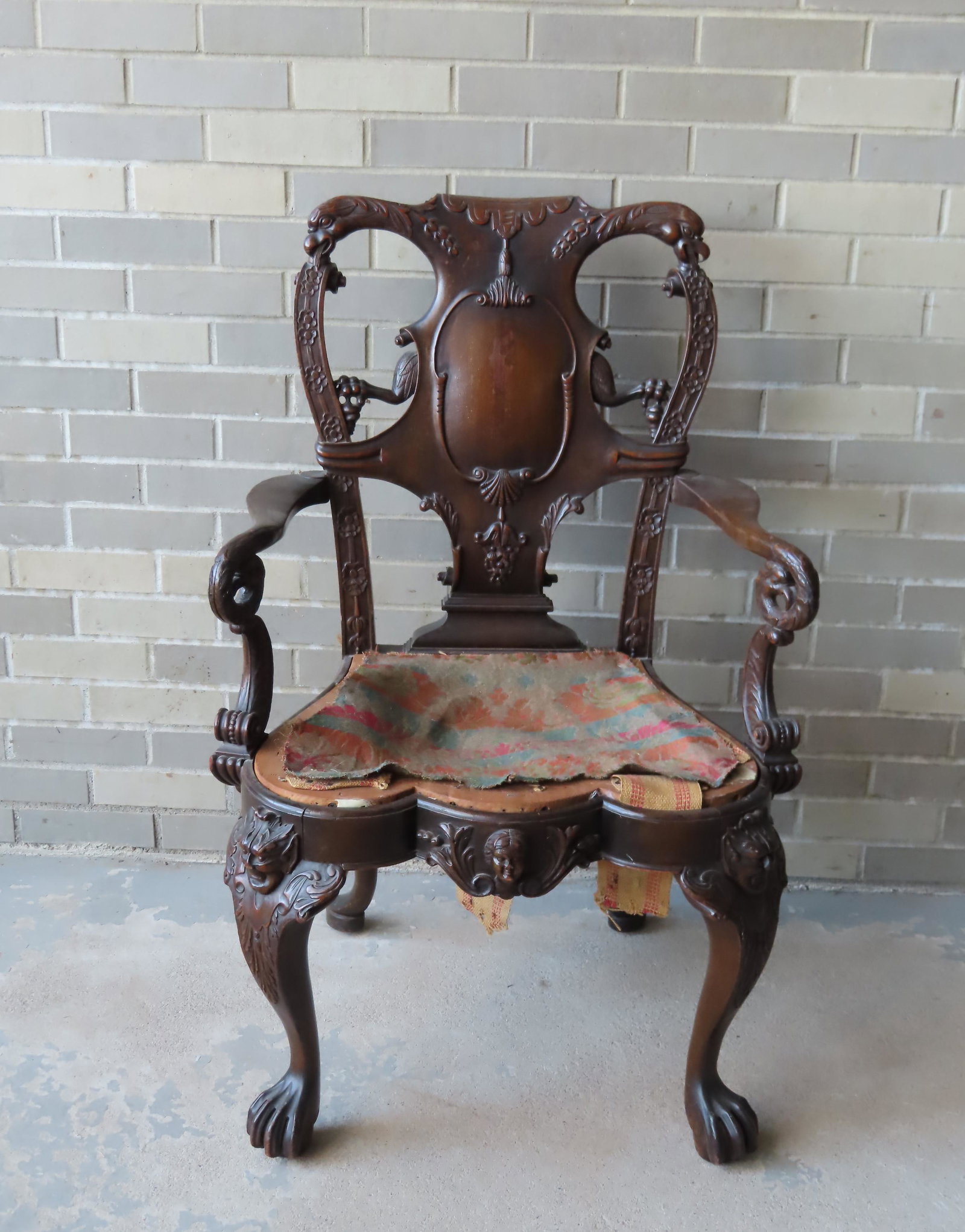An ornate and heavily carved Chippendale style arm: An ornate and heavily carved Chippendale style arm chair having a crest with carved eagle heads that hold scrolls that extend from the top of the stiles, a back splat with scrolled panel and eagle leg