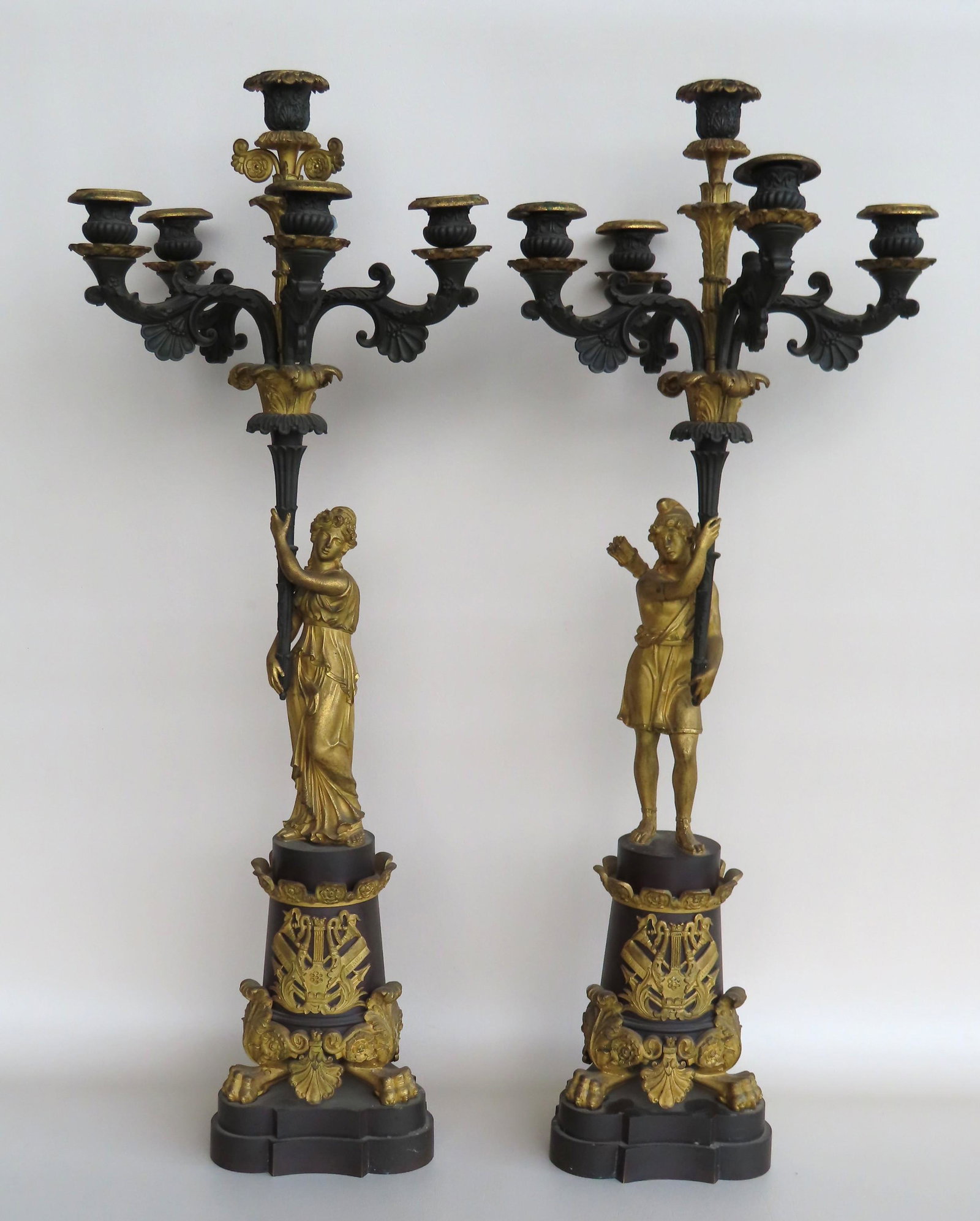 A pair of gilded bronze 5 light candelabras with goose: A pair of gilded bronze 5 light candelabras with goose neck lyre applied to front marked Iliade and Odissee (The Iliad and Odyssey) - acanthus ornaments leading to claw feet on a shaped stepped bronze