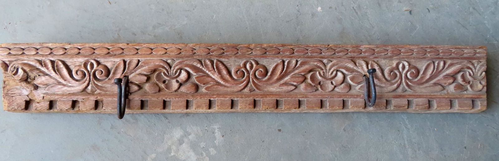 A carved oak hat rack, 18th century.: A carved oak frieze board, likely 18th century, that has been reworked to use as a coat rack. Note that the 2 iron hooks applied at a later date are hand forged iron. There exists an expansion crack a