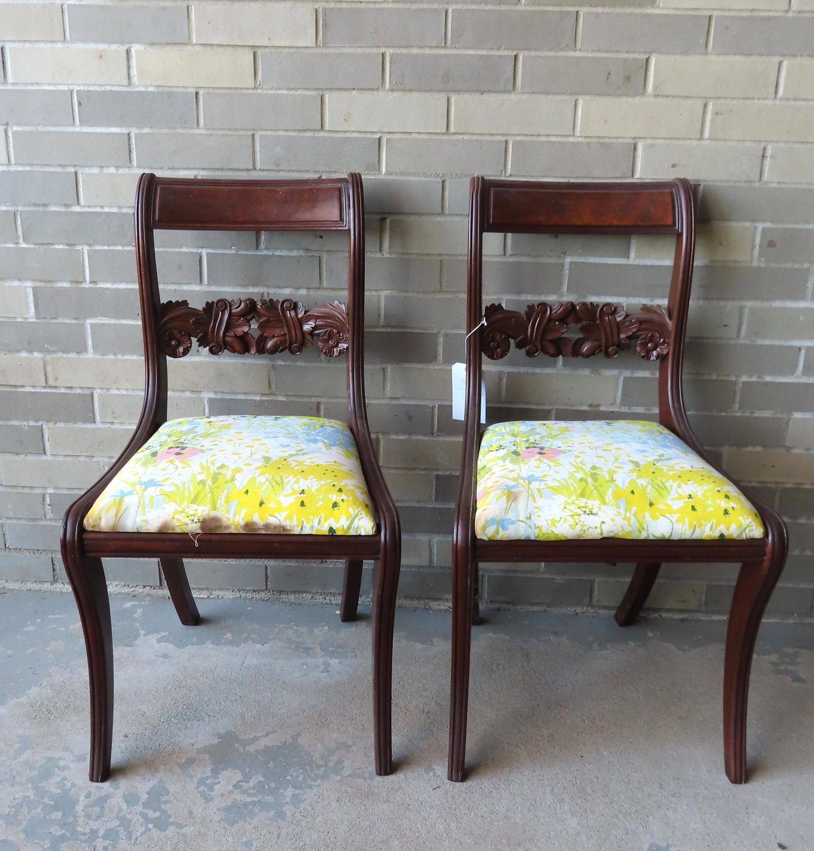A pair of American Sheraton side chairs with reeded: A pair of American Sheraton side chairs with reeded stiles and having an acanthus carved central back splat with carved rosette terminals. Each chair measures 32 1/2"H x 18"W x 17"D x 17"H (to top of 