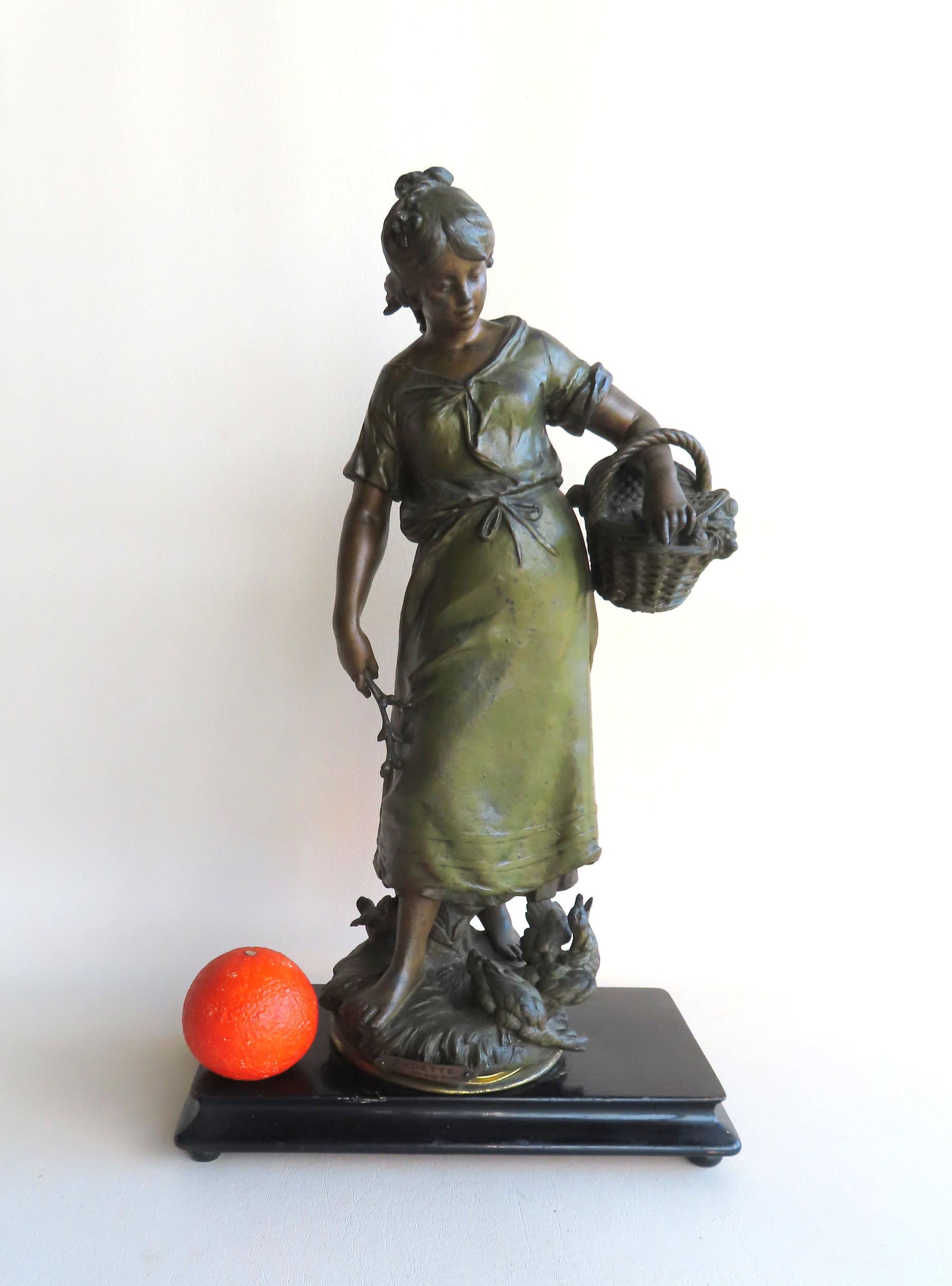 Auguste Moreau, French 1834-1917. A metal cast: Auguste Moreau, French 1834-1917. A metal cast sculpture with bronze finish depicting a standing lady holding a basket in one arm and a sprig of flowers in other hand with ducks near her feet. Brass p