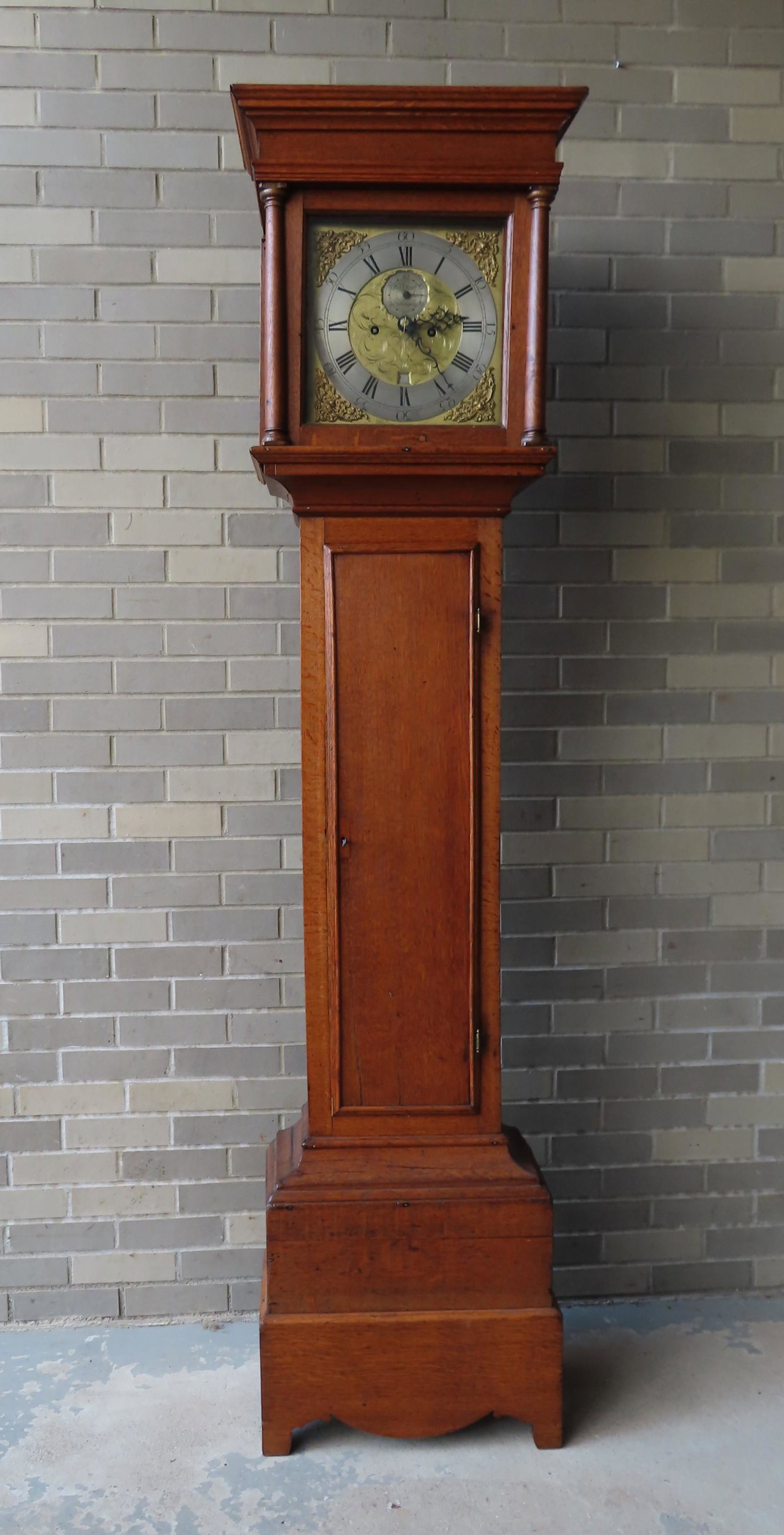 A Chippendale English oak tall case clock signed on: A Chippendale English oak tall case clock signed on brass and silver dial "Willm Clark / Coningsby" - the face with second hand and calendar and has winged cherubs in corners. The bonnet with stepped 
