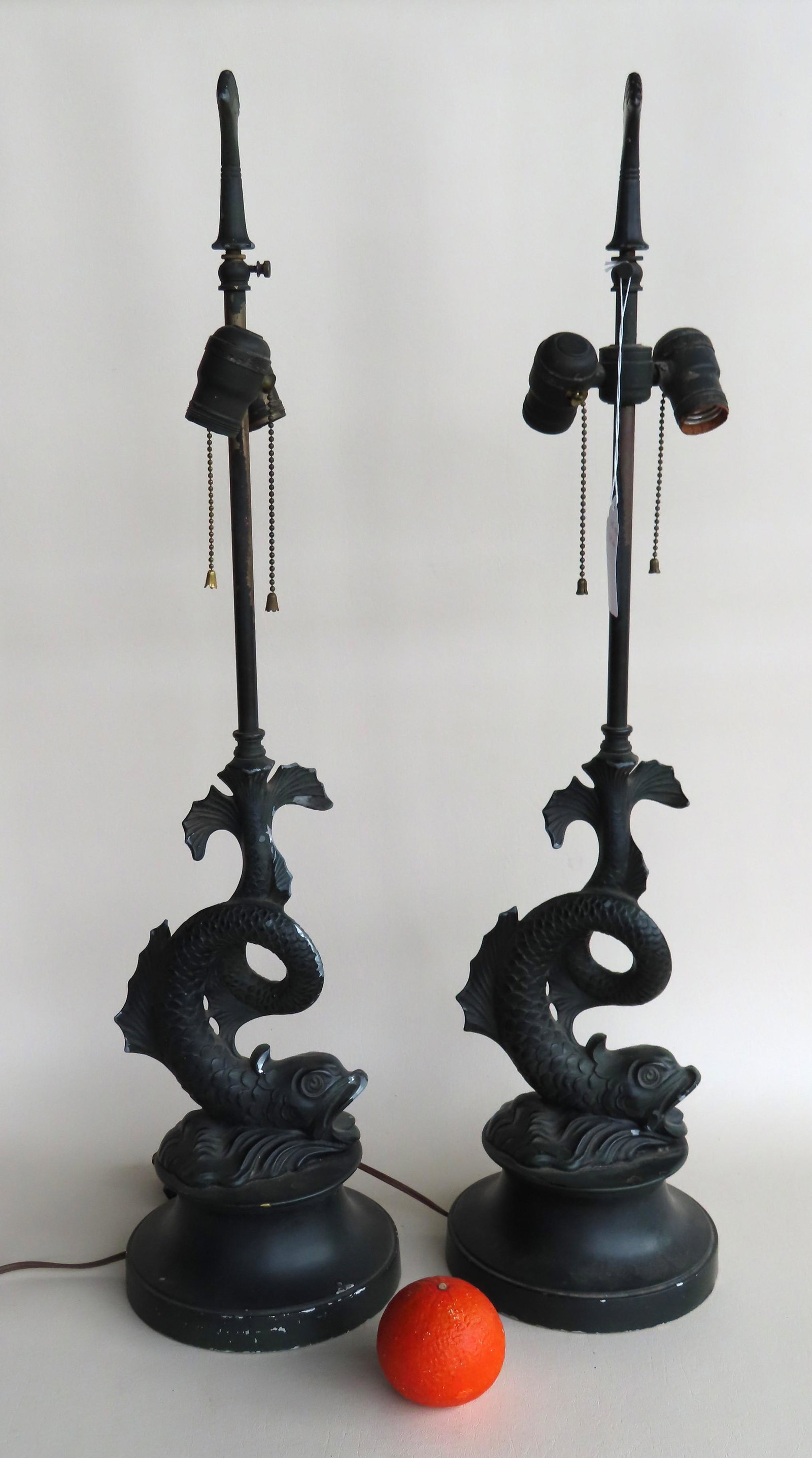Pair of dolphin form white metal table lamps in: Pair of dolphin form white metal table lamps in original black paint, mid 20th century. Slight use wear to paint, otherwise good condition. Each measures 30 1/2"H x 7 1/2" diameter at base.