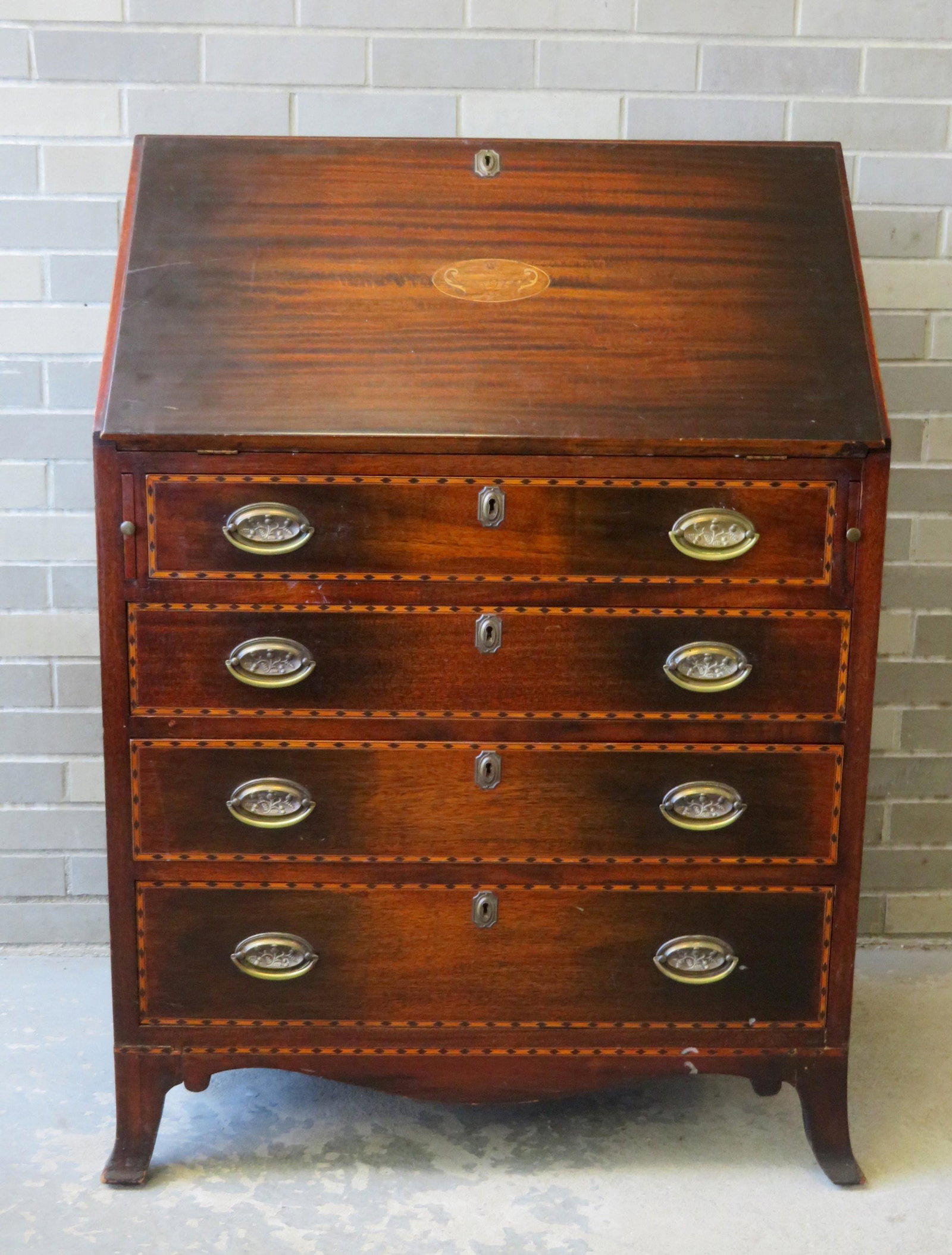A mahogany Hepplewhite style slant front desk, custom: A mahogany Hepplewhite style slant front desk, custom made, late 19th century with inlays. The desk with a fitted interior over 4 graduated drawers with checkered inlay banding over French feet. Some 