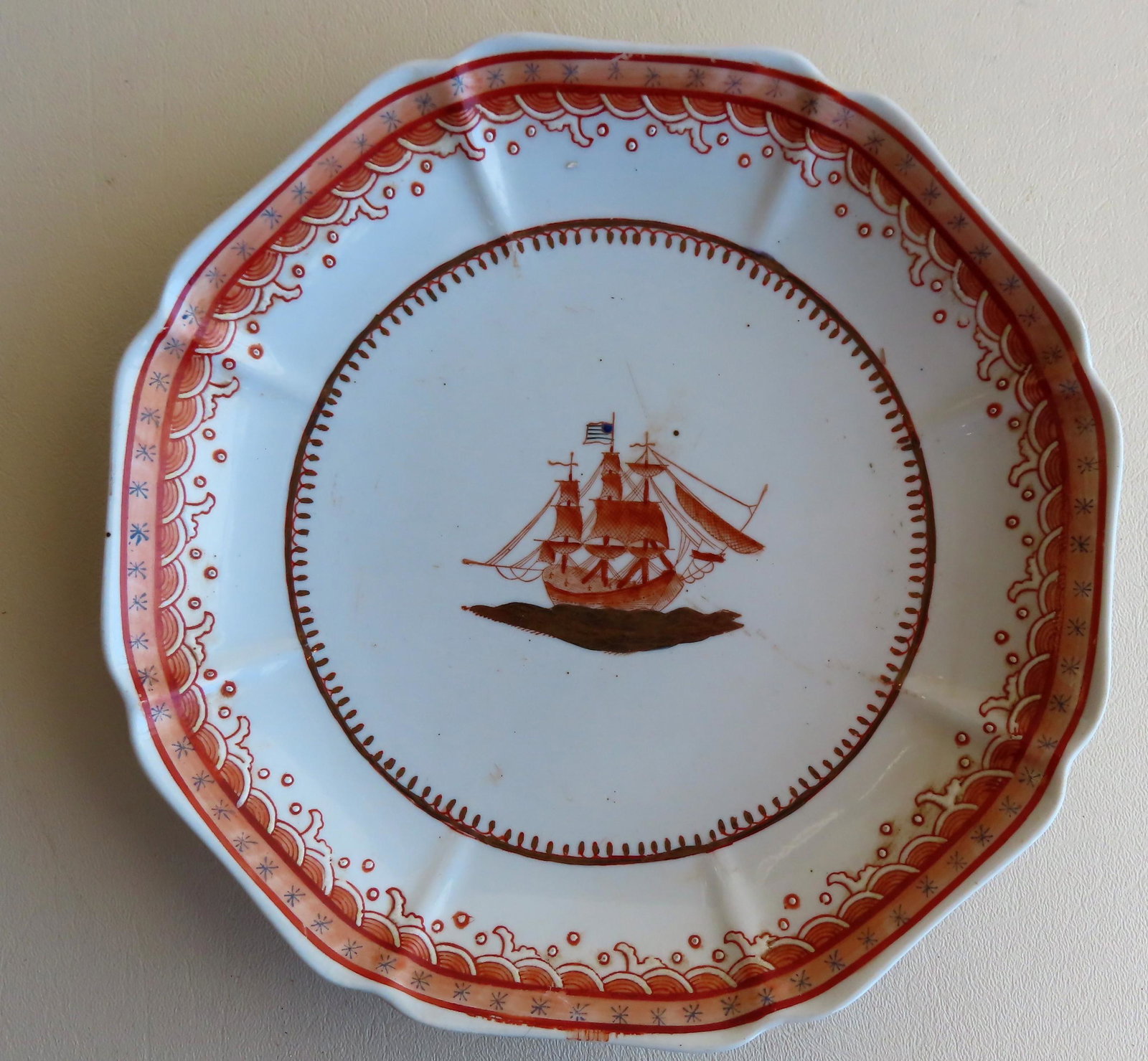 Chinese export plate with a central hand painted image: Chinese export plate with a central hand painted image of a 3 mast sailing ship bearing an American flag - salmon color paint - 8 3/4"D. Very good condition. Early 19th century.