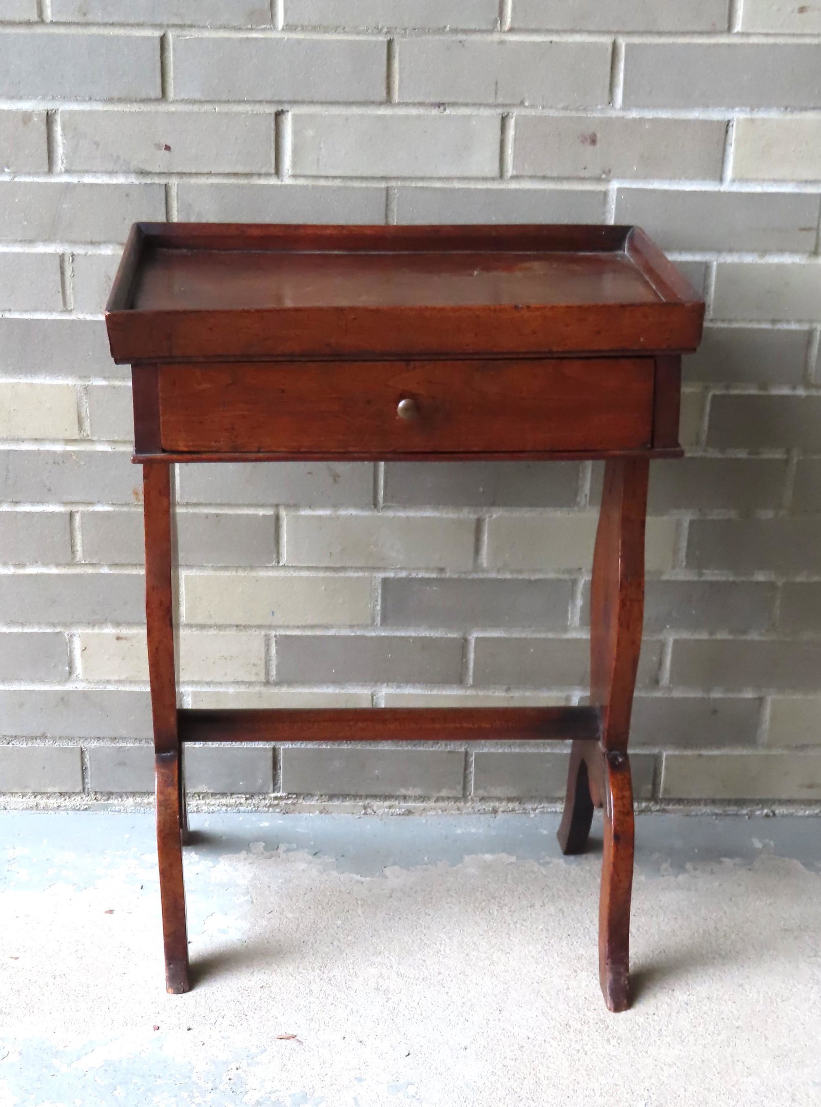 A small continental fruit wood work table or tea table: A small continental fruitwood work table or tea table with a rectangular dish top with chamfered edges over one drawer, vase-shaped sides supported by cross-stretcher leading to 2 snake feet on both s