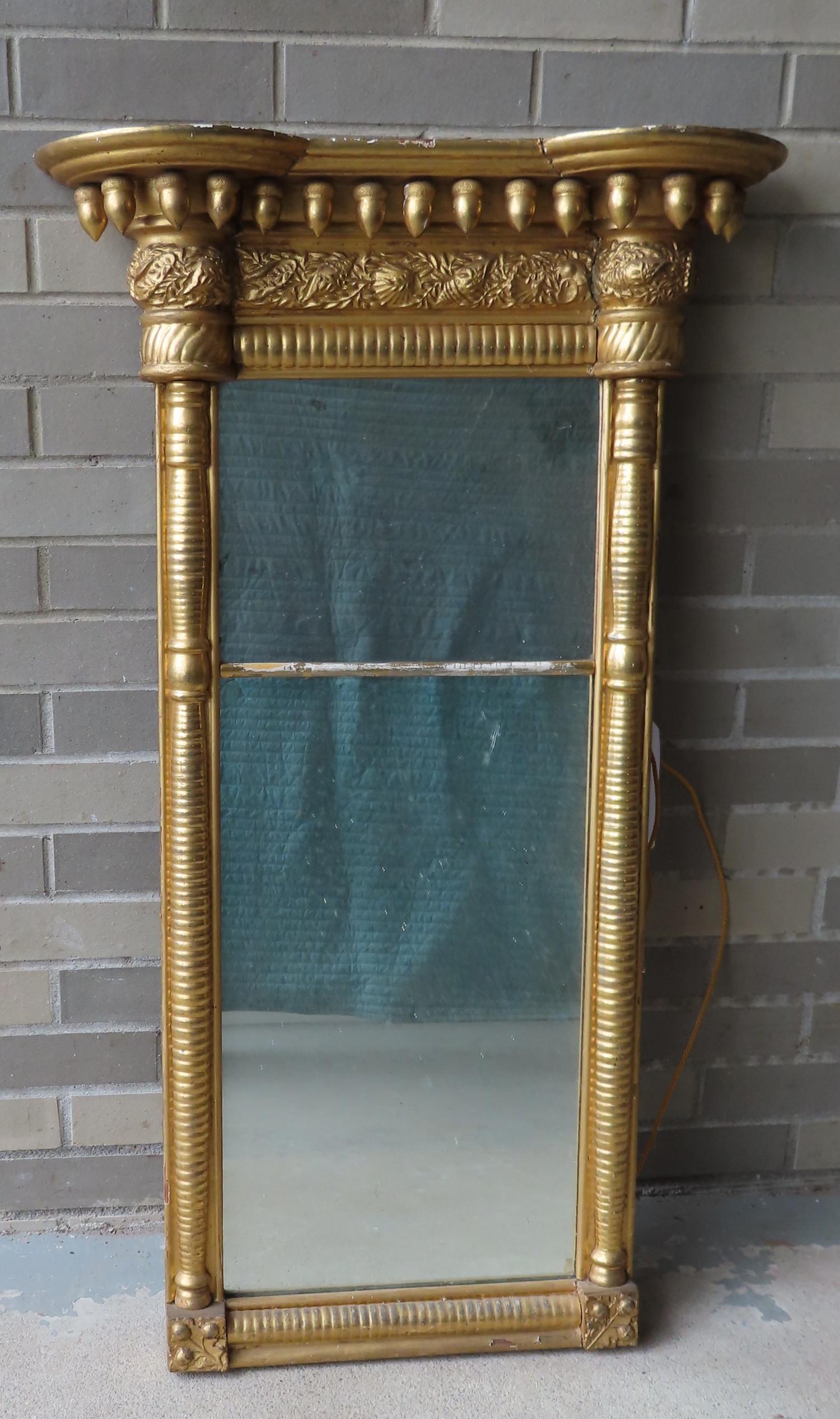 A Sheraton double panel wall mirror having a shaped: A Sheraton double panel wall mirror having a shaped crest decorated with carved gilded gesso over wood acorns over a frieze board with gesso leaves - turned 1/2 columns flank the mirror and lead to sm