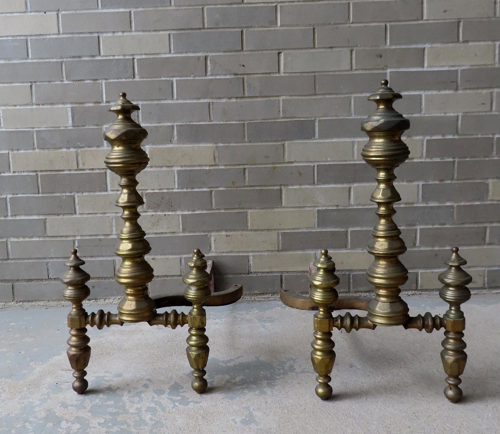 A large pair of Chippendale brass andirons having a: A large pair of Chippendale brass andirons having a central turned post flanked by 2 matching smaller turned posts - missing one stopper and rear leg on each piece, otherwise good condition - 25"H x 1