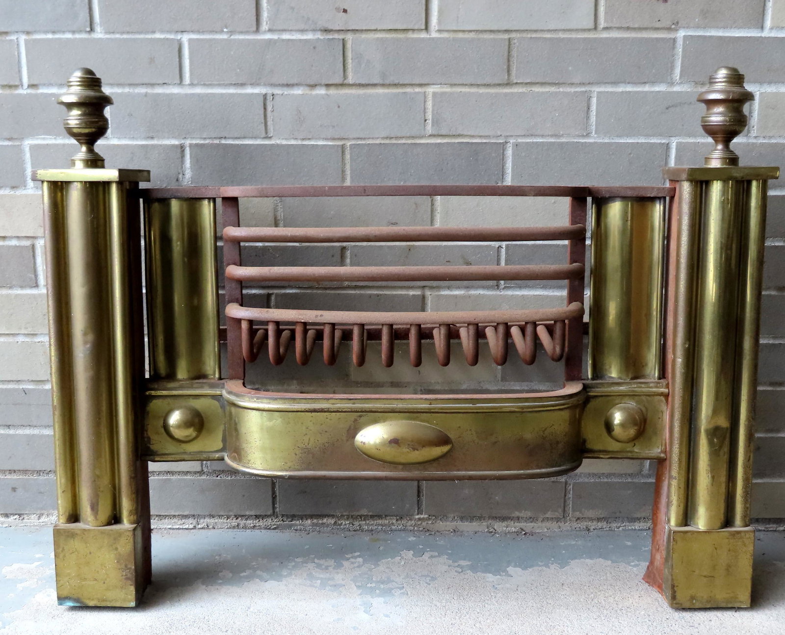 A brass fireplace fender with built in grill and shaped: A brass fireplace fender with built in grill and shaped front, possible the front of a Franklin stove, circa 1850. The front with reeded columns and turned brass finials. Good condition. Measures 34"W