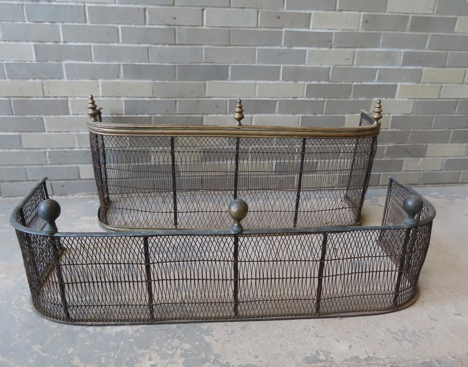 Two early brass and wire mesh fireplace fenders. The: Two early brass and wire mesh fireplace fenders. The first with 3 ball finials and measures 44 1/2"W x 13"H x 16 1/4"D - small impressions in wire, otherwise very good condition; the second with 3 tur