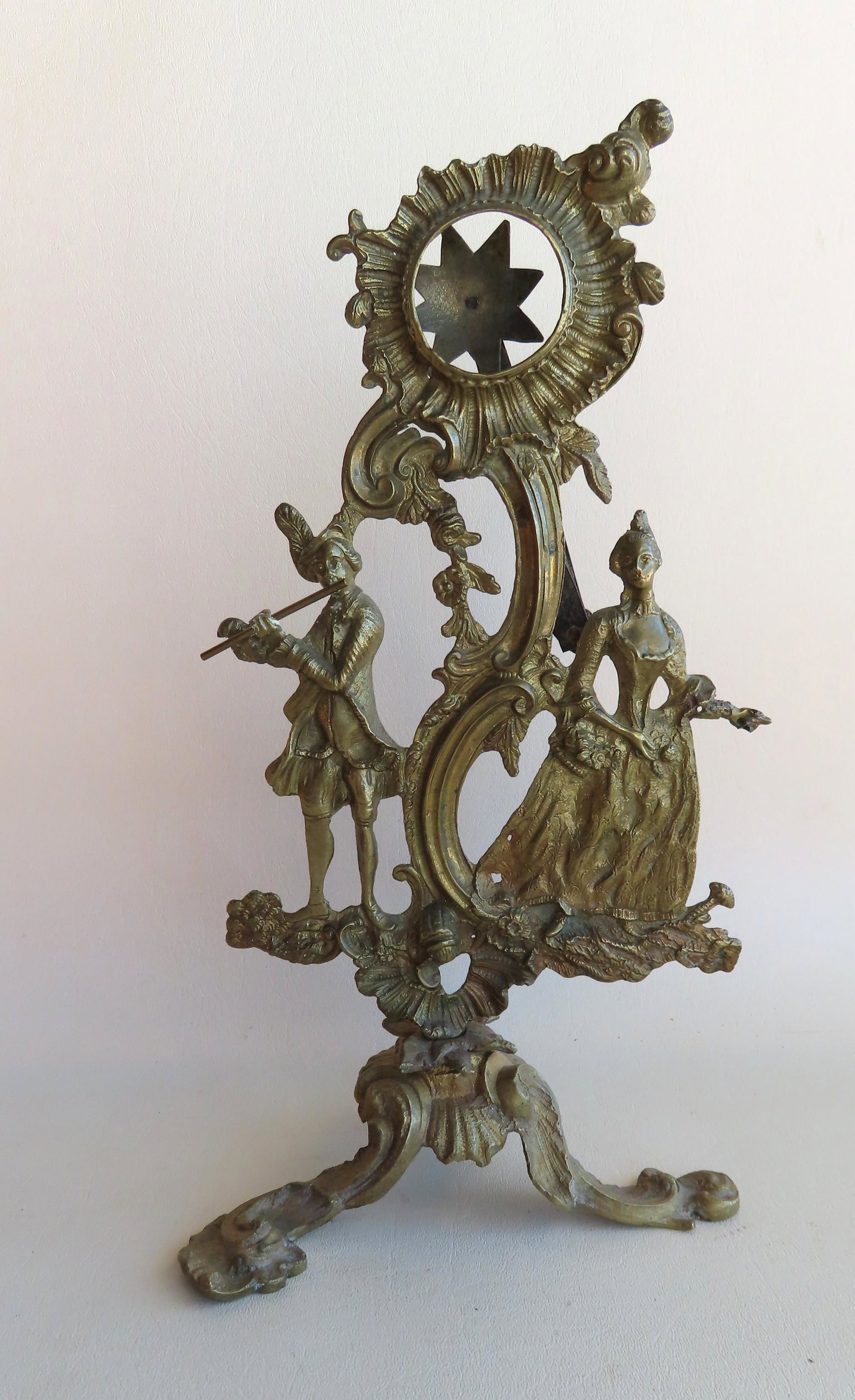 Early French rococo style brass watch holder, depicting: Early French rococo style brass watch holder, depicting a man playing flute and woman with arm extended, allegedly holding a cup which is missing - spring release mechanism on reverse side, mid to lat