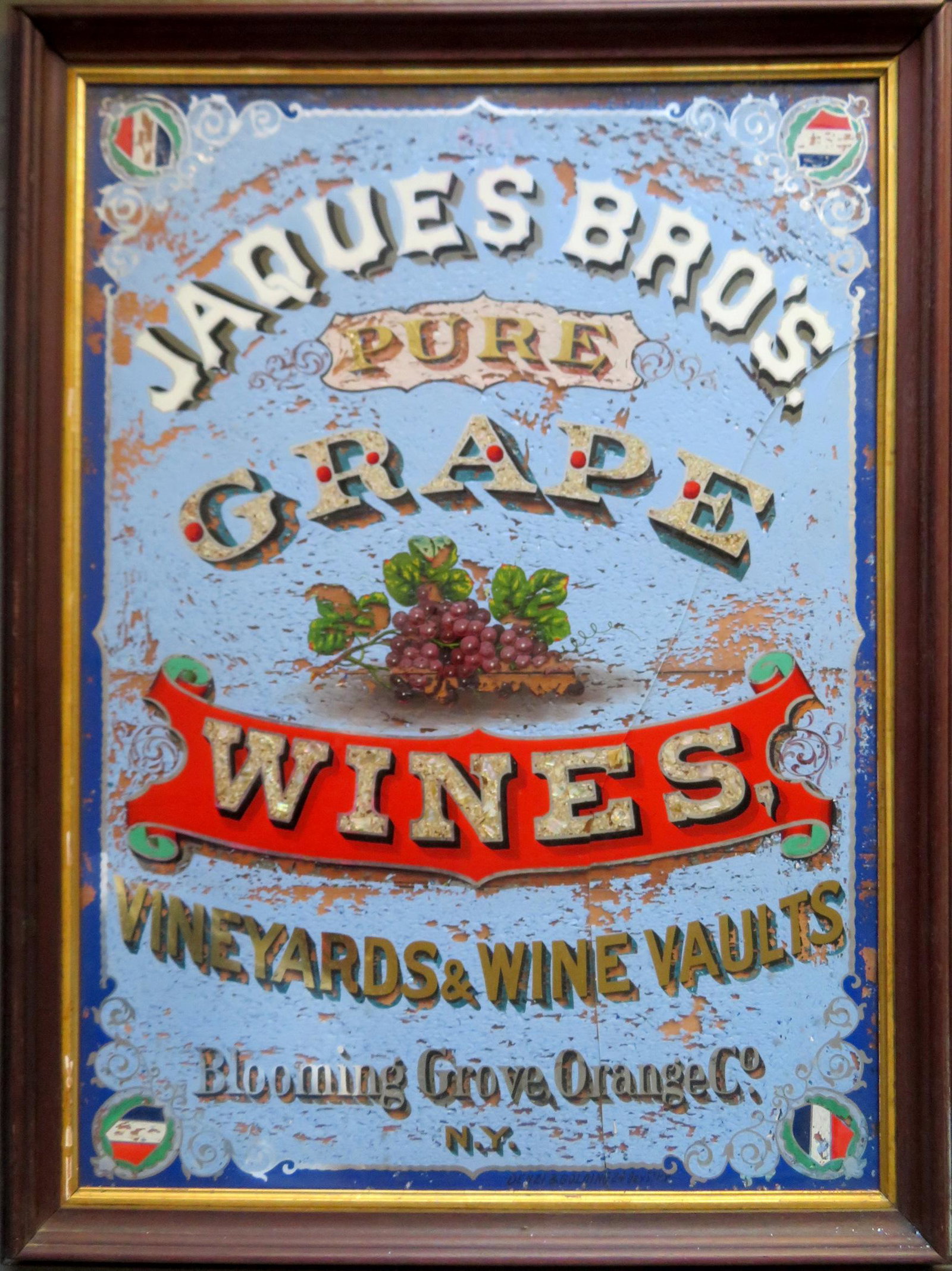 A colorful advertising sign hand painted in reverse on: A colorful advertising sign hand painted in reverse on glass "JAQUES BRO'S. / PURE GRAPE WINES / VINEYARDS & WINE VAULTS / BLOOMING GROVE, ORANGE Co., N.Y." - original black walnut frame, circa 1870-8