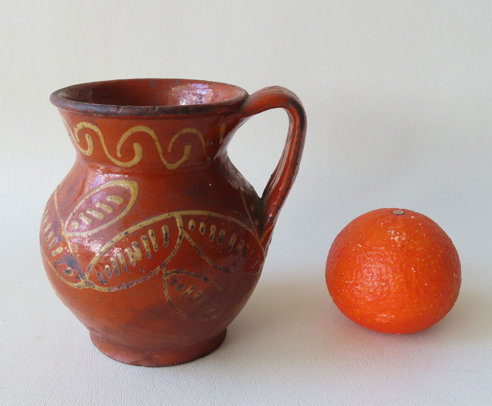 Redware pitcher decorated in slip with stylized leaves (1 of 4)