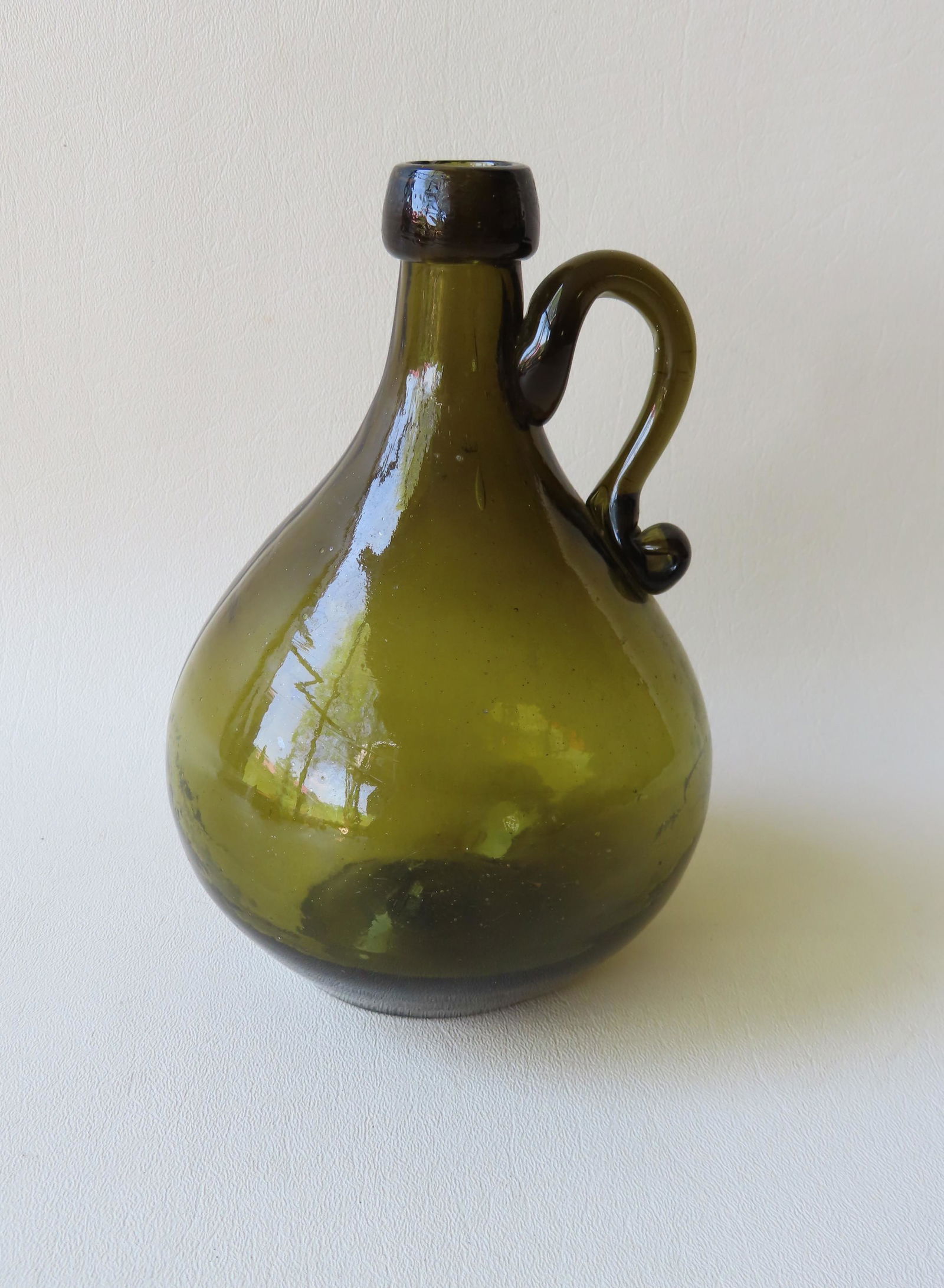 A bulbous dark olive green hand blown glass whiskey jug (1 of 4)