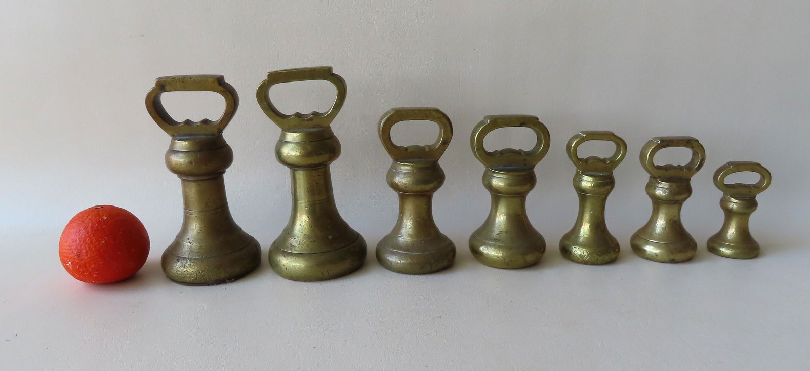 A grouping of 7 bell shaped cast brass scale weights (1 of 4)
