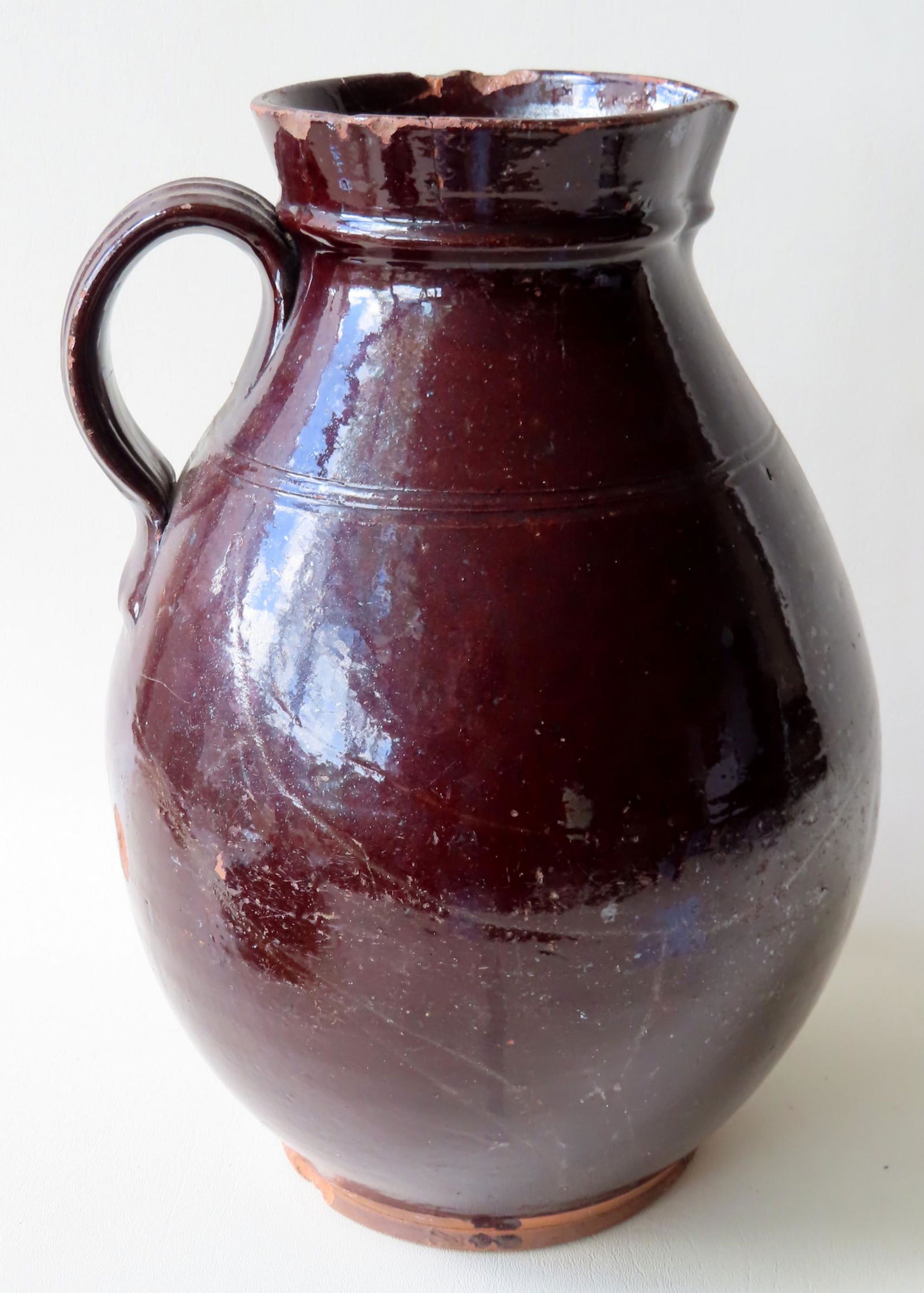 A large redware pitcher with Albany glaze, having a (1 of 4)