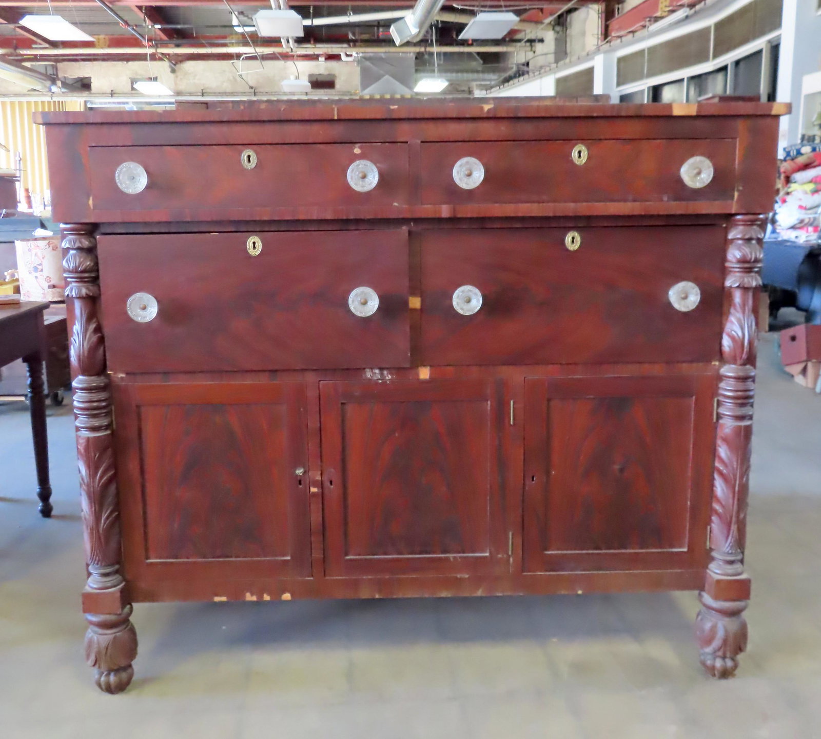 An Empire sideboard with Sandwich glass pulls: An Empire sideboard having 2 short and narrow drawers over 2 larger drawers, all with original sandwich glass pulls, over 2 doors, flanked by acanthus carved half columns terminating in acanthus carve