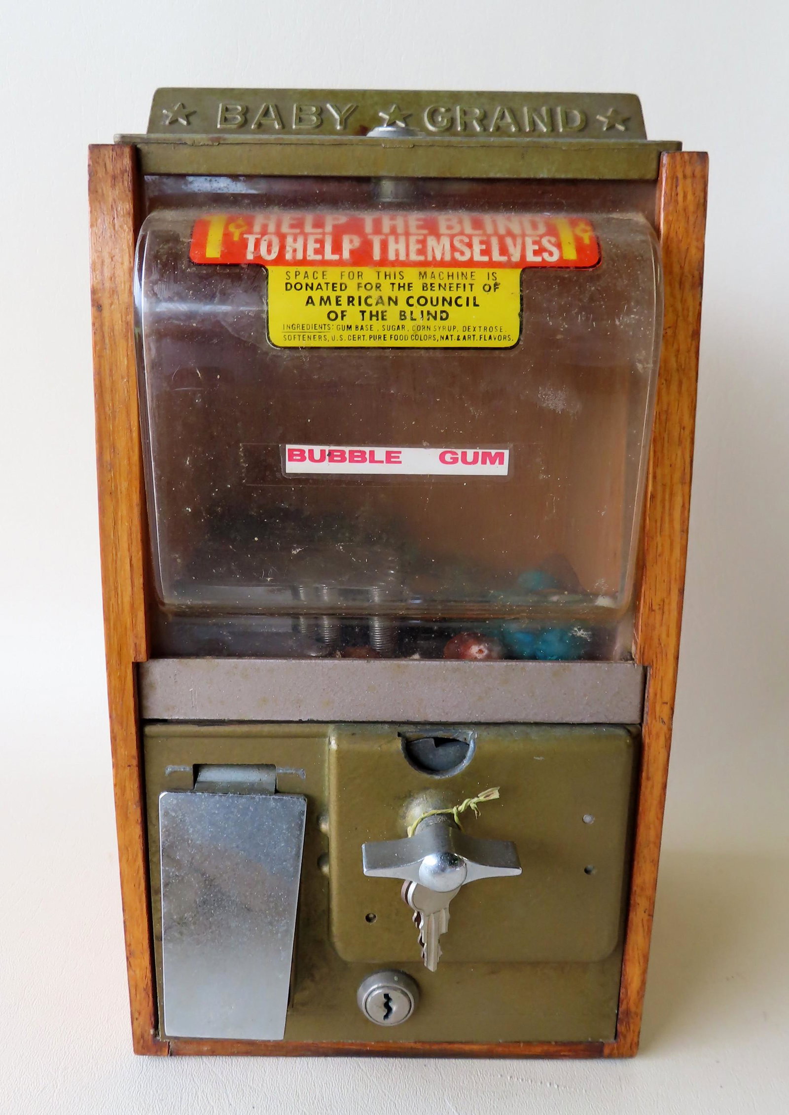 A table top "Baby Grand" 1 cent bubble gun machine with: A table top "Baby Grand" 1 cent bubble gun machine with oak case, very good working condition. The front with a sticker marked "Space For This Machine Is Donated For The Benefit Of American Council Of
