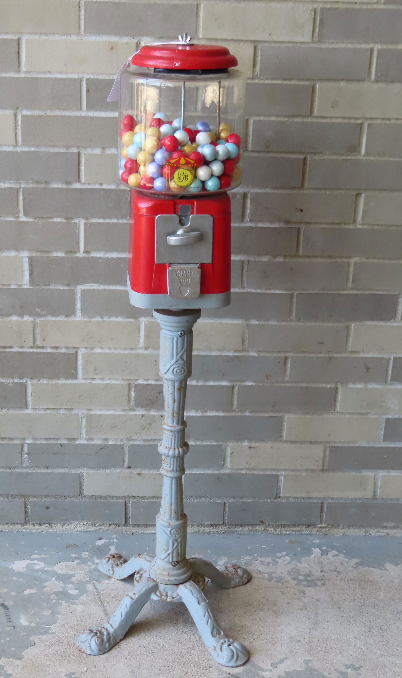 Floor standing 5 cent bubble gum machine mounted on a: Floor standing 5 cent bubble gum machine mounted on a fancy cast metal base, circa 1980. The glass dome with sticker marked "Carousel Industries Inc." - measures 42 1/4"H x 16 1/2"W at base. The mecha