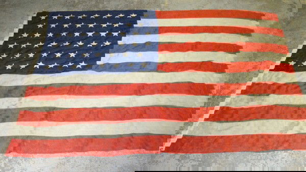 Four American flags: 46 star 4'8" x 7'3", 48 star: Four American flags: 46 star 4'8" x 7'3", 48 star 4'5" x 7'6" (with tear), 48 star 3' x 5', plus a nautical flag approx 3'x5'