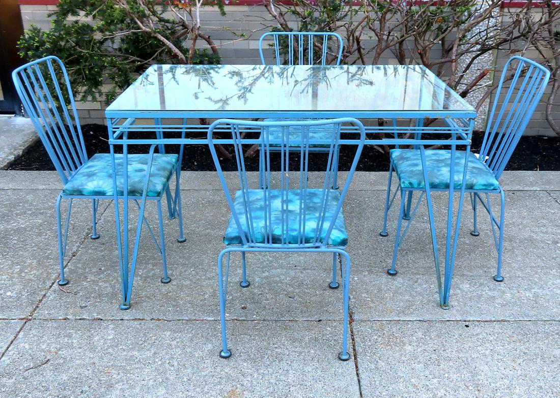 A high quality wrought iron patio set in the mid: A high quality wrought iron patio set in the mid century modern style, circa 1950-60, in an older blue paint, unknown maker. The rectangular glass top table measures 48"L x 30"W x 30 1/4"H. Both the c