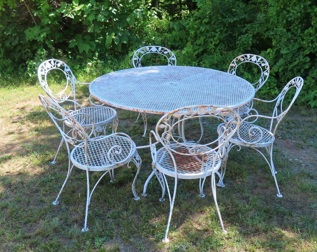 A wire mesh patio set consisting of a round table: A wire mesh patio set consisting of a round table measuring 48" diameter x 28 1/4"H, and 6 chairs decorated with flowers and leaves on vines - some surface rust but overall good condition.