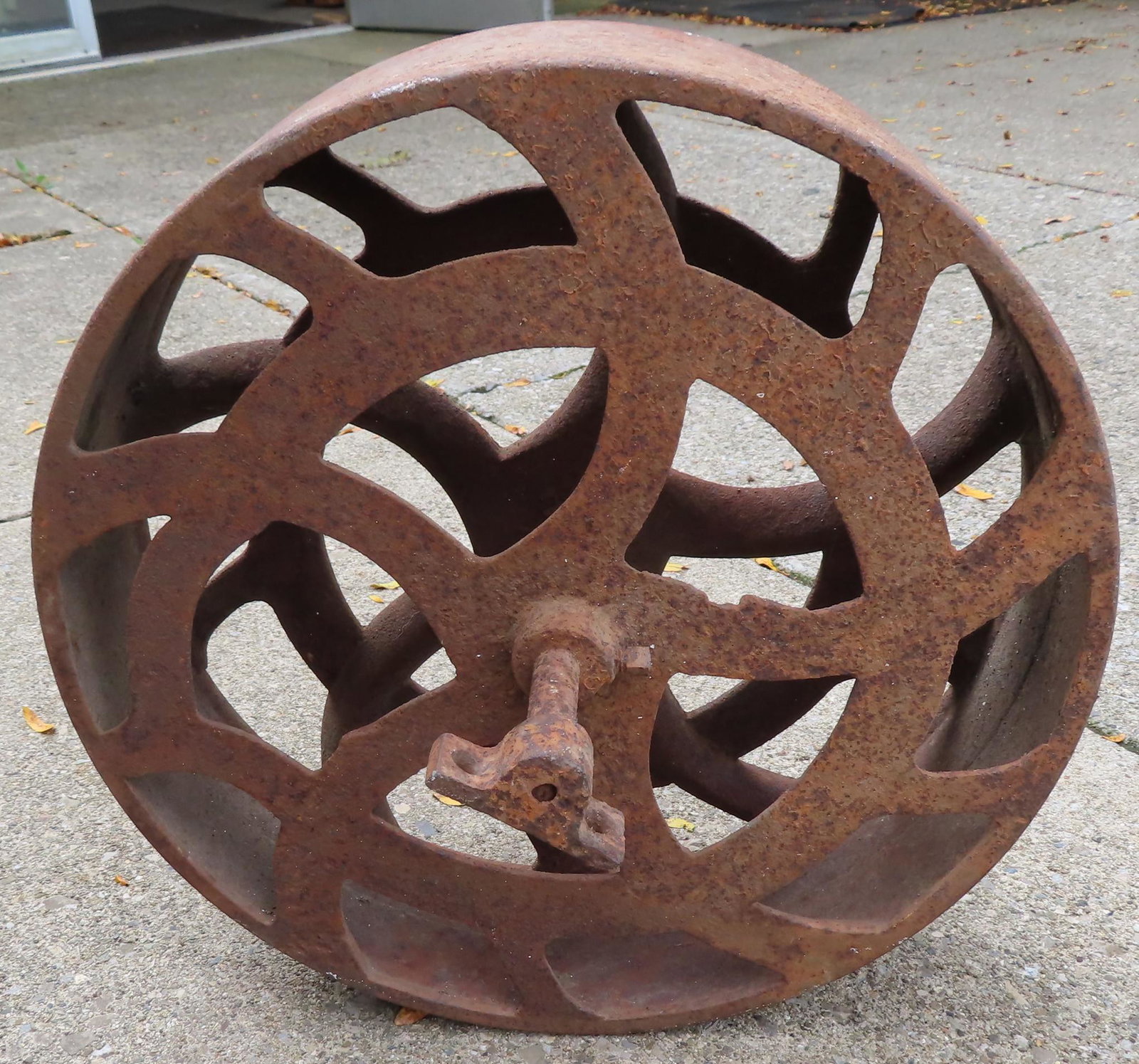 An industrial cast iron wheel with artistic cutout: An industrial cast iron wheel with artistic cutout spoke design, late 19th century - 18" diameter x 5"W wheel x 15"W (axel end to axel end) . Some surface rust, but overall good condition.