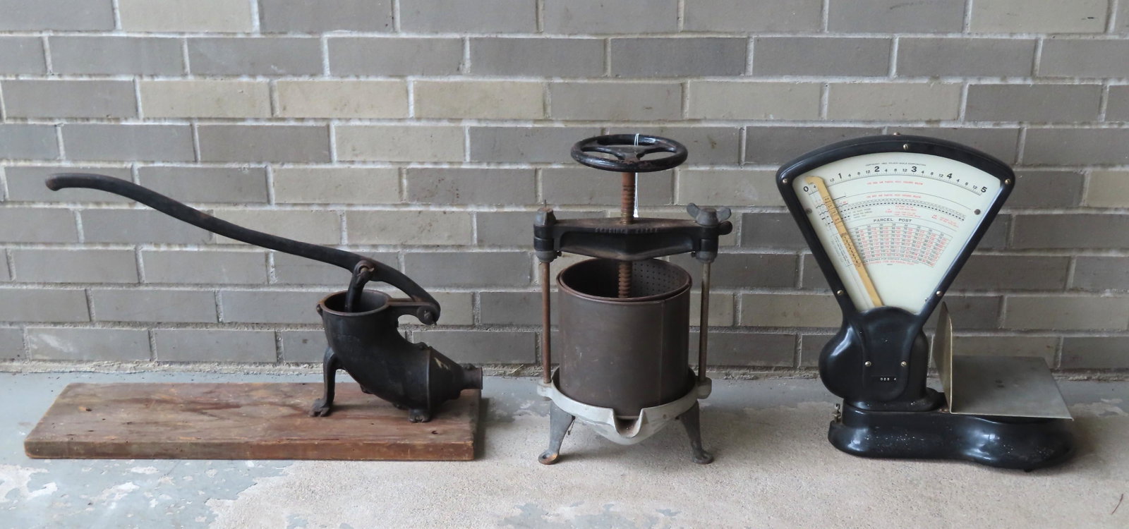 Three country collectibles including: A primitive iron: Three country collectibles including: A primitive iron farmhouse sausage stuffer mounted on wooden plank - good condition - 29"L x 8"W x 10"H - late 19th century; an iron and tin fruit press marked "S