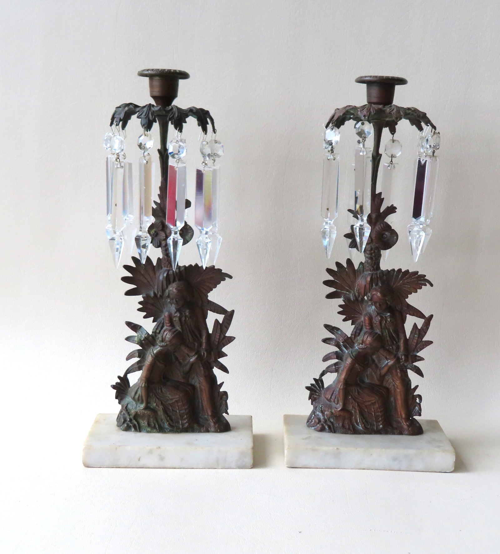 Pair of 19th century bronze girandoles with glass: Pair of 19th century bronze girandoles with glass prisms mounted on rectangular marble base; romantic scene with boy and girl near tree and flowers. The prisms with very slight imperfections - the bro