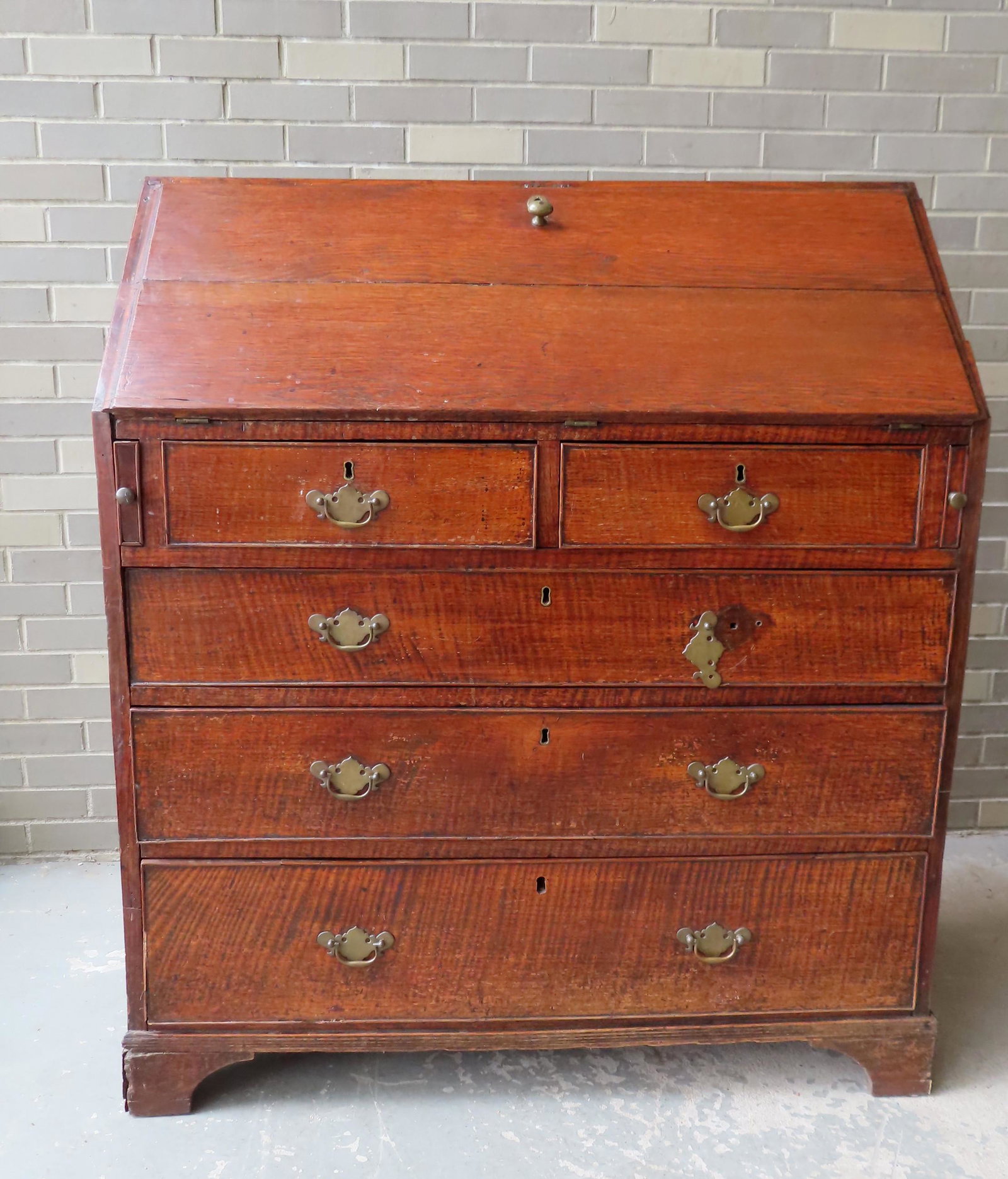 A Chippendale slant front desk in oak with strong tiger: A Chippendale slant front desk in oak with strong tiger graining on drawers (unidentified wood on drawers) mounted on bracket base and fitted interior with drawers. Dovetailed case and rose head nail 