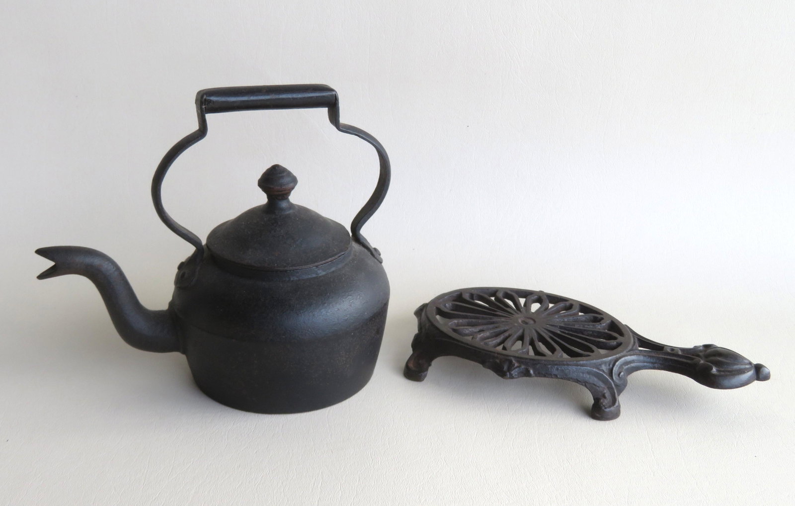 A small cast iron goose neck tea kettle, with impressed: A small cast iron goose neck tea kettle, with impressed mark "1" on base - 7 1/2"H x 8 1/2"W; combined with a stylized turtle shaped iron trivet - 9 3/4"L x 5"W x 1 1/4"H. Both mid 19th century or ear