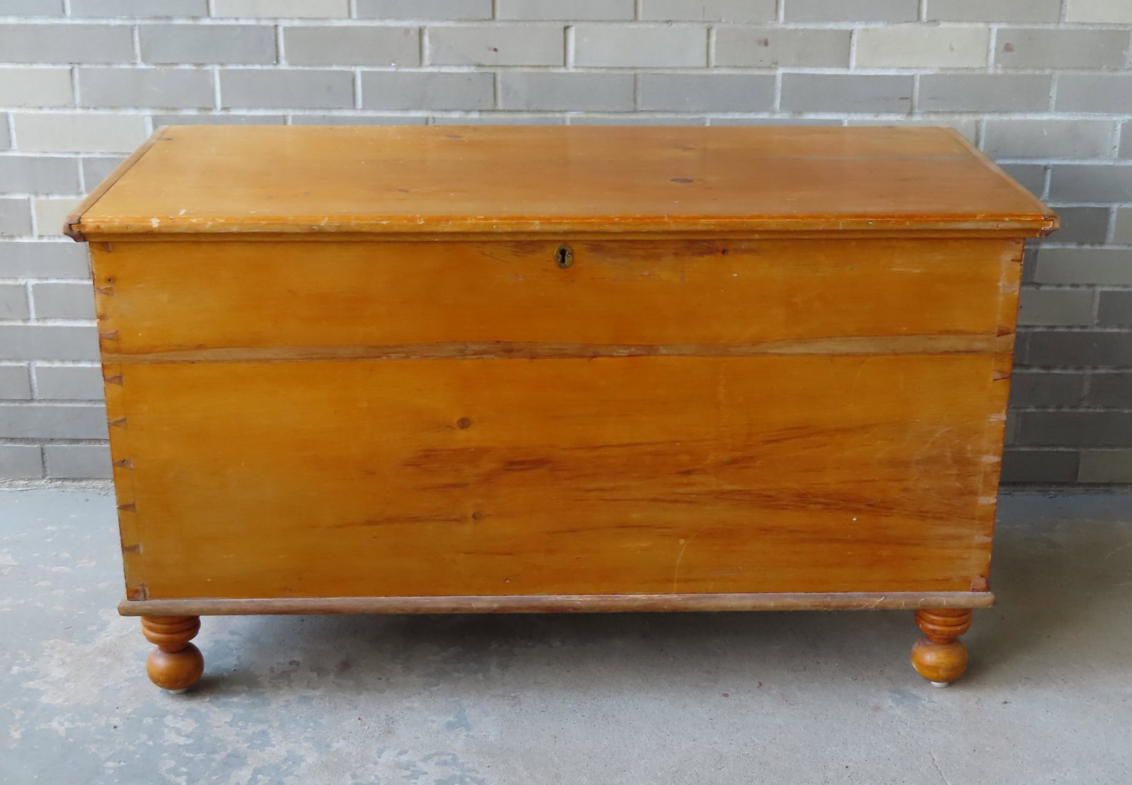 A refinished pine blanket box on short turned legs: A refinished pine blanket box on short turned legs leading to ball feet, and also having an interior till, mid 19th century, dovetailed construction. Narrow stain across the front, use wear to top, ov