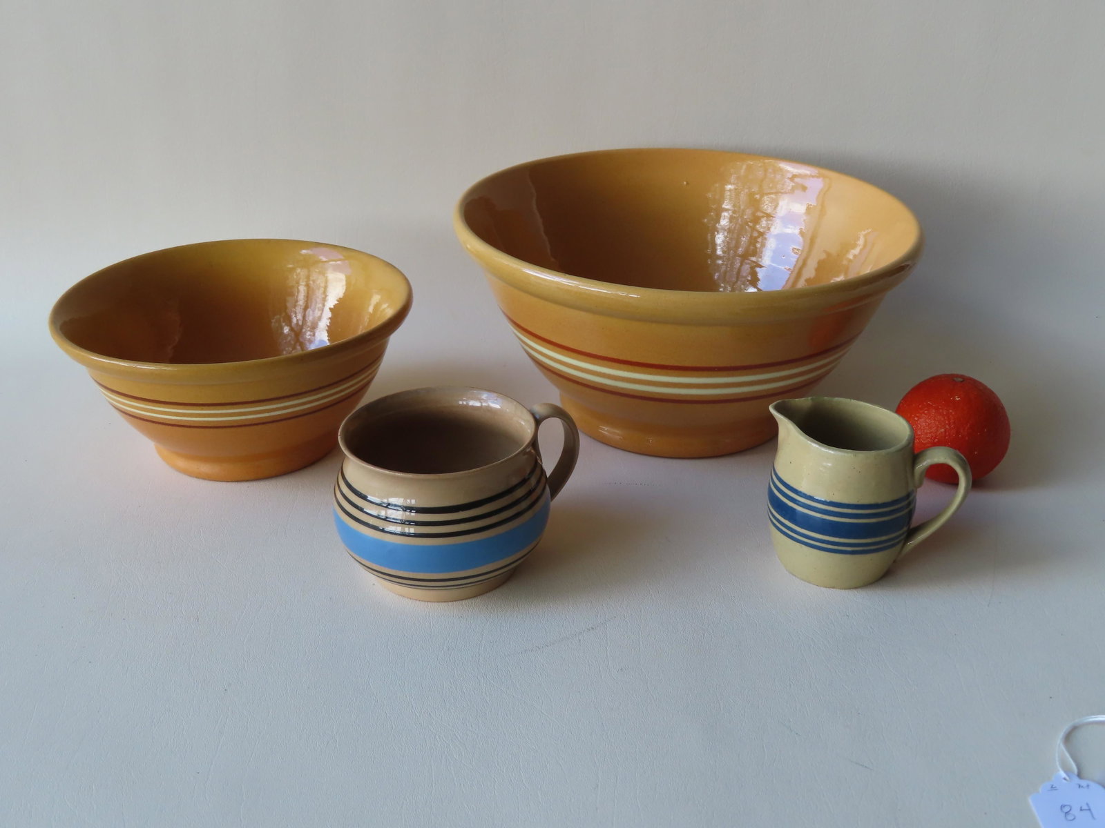 Grouping of 4 pieces of earthenware including: Two: Grouping of 4 pieces of earthenware including: Two matching yellowware bowls with rolled rims, footed base and having a body decorated with 2 white and 2 brown horizontal bands, both in very good cond