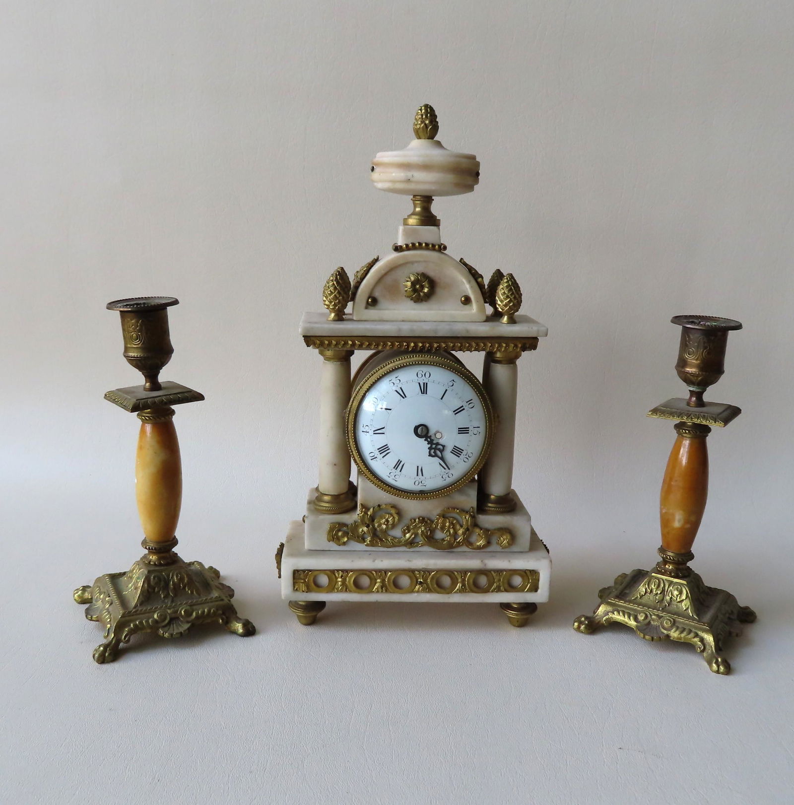 A small grouping of decorative objects including: A: A small grouping of decorative objects including: A French Empire period marble and gilded bronze mantle clock with double columns opposite the clock face and having ormolu and pineapple finials - the