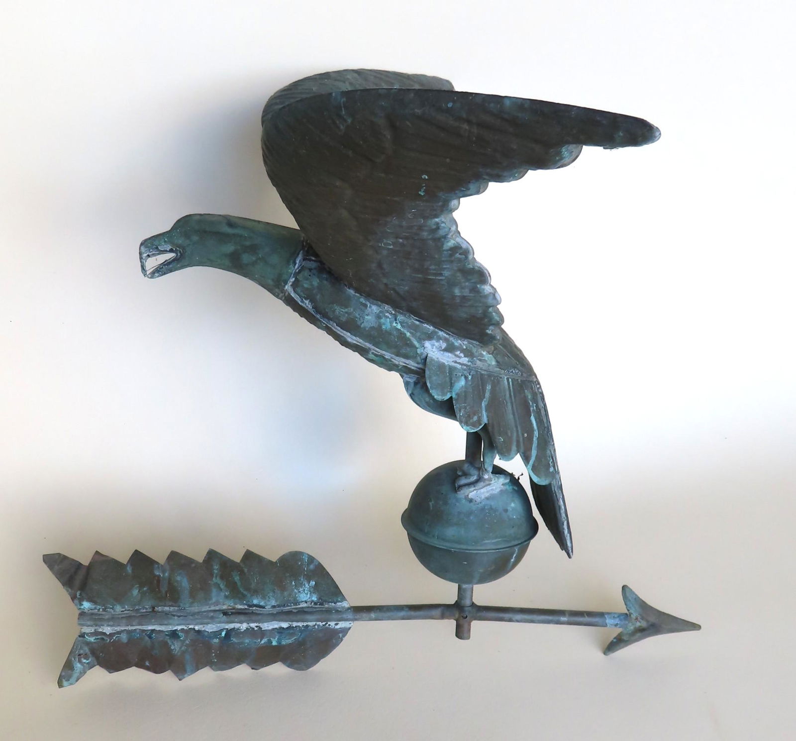 A full body copper spread wing eagle weathervane: A full body copper spread wing eagle weathervane with patination, mounted on orb that is mounted on arrow directional with zinc point, circa 1950-70. The arrow measures 21 3/4"L and the eagle measures