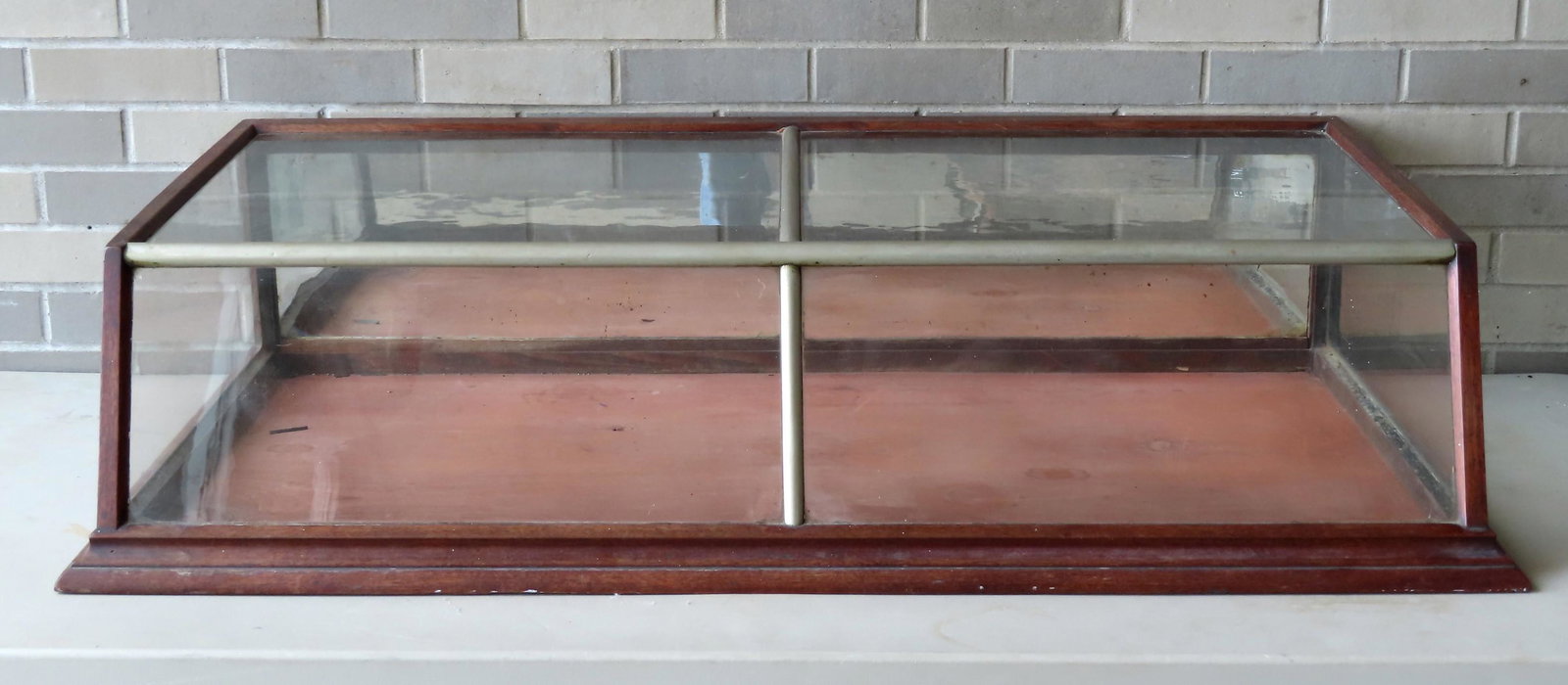 Country store table top showcase with slant front and: Country store table top showcase with slant front and having a metal and wood frame and 2 original pull down doors with mirror backs on reverse side - 46"W x 24 1/4"D x 11"H - appears to be all origin